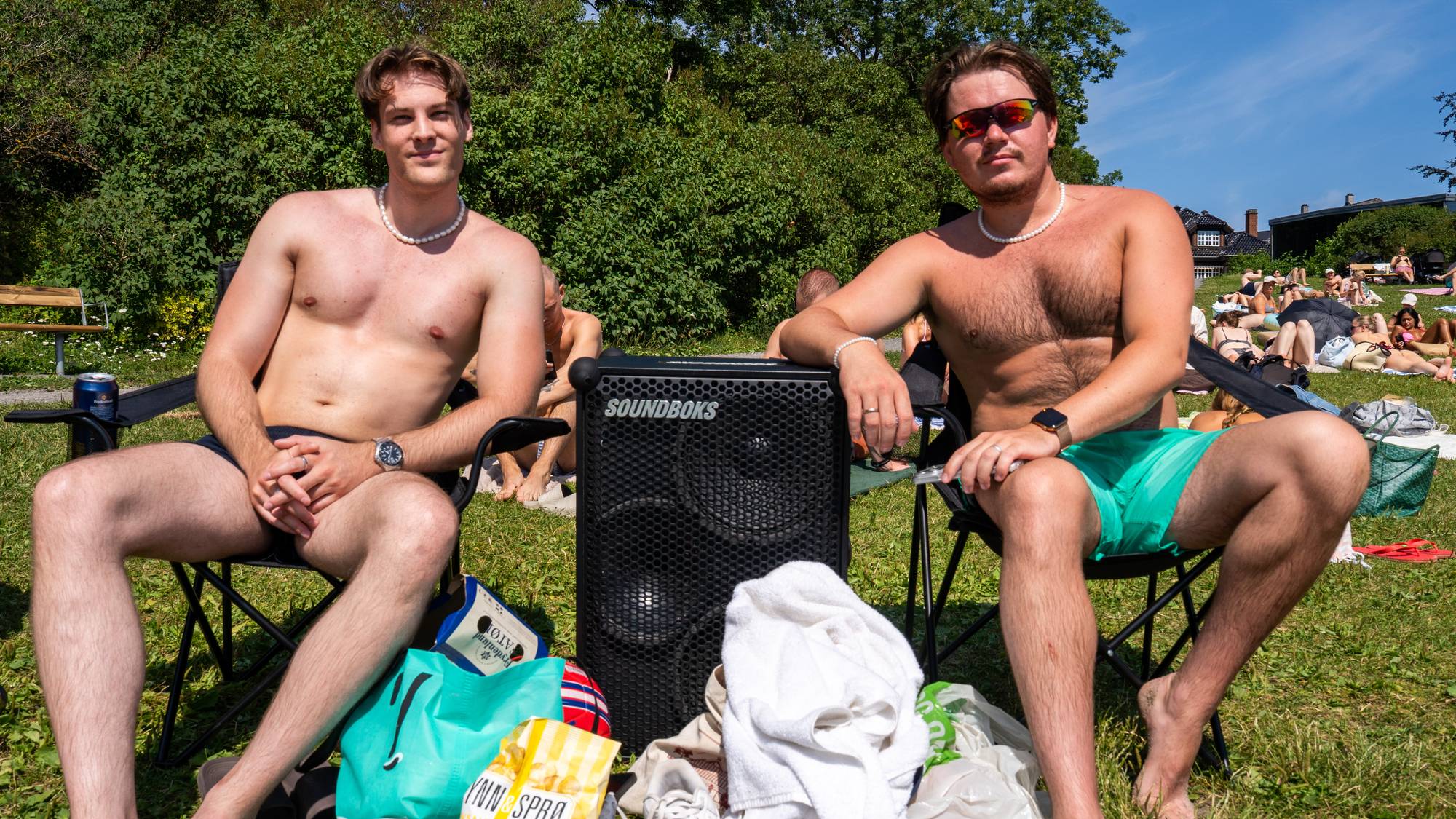 To menn sit i campingstolar på gressplen, på kvar si side av ein høgtalar.