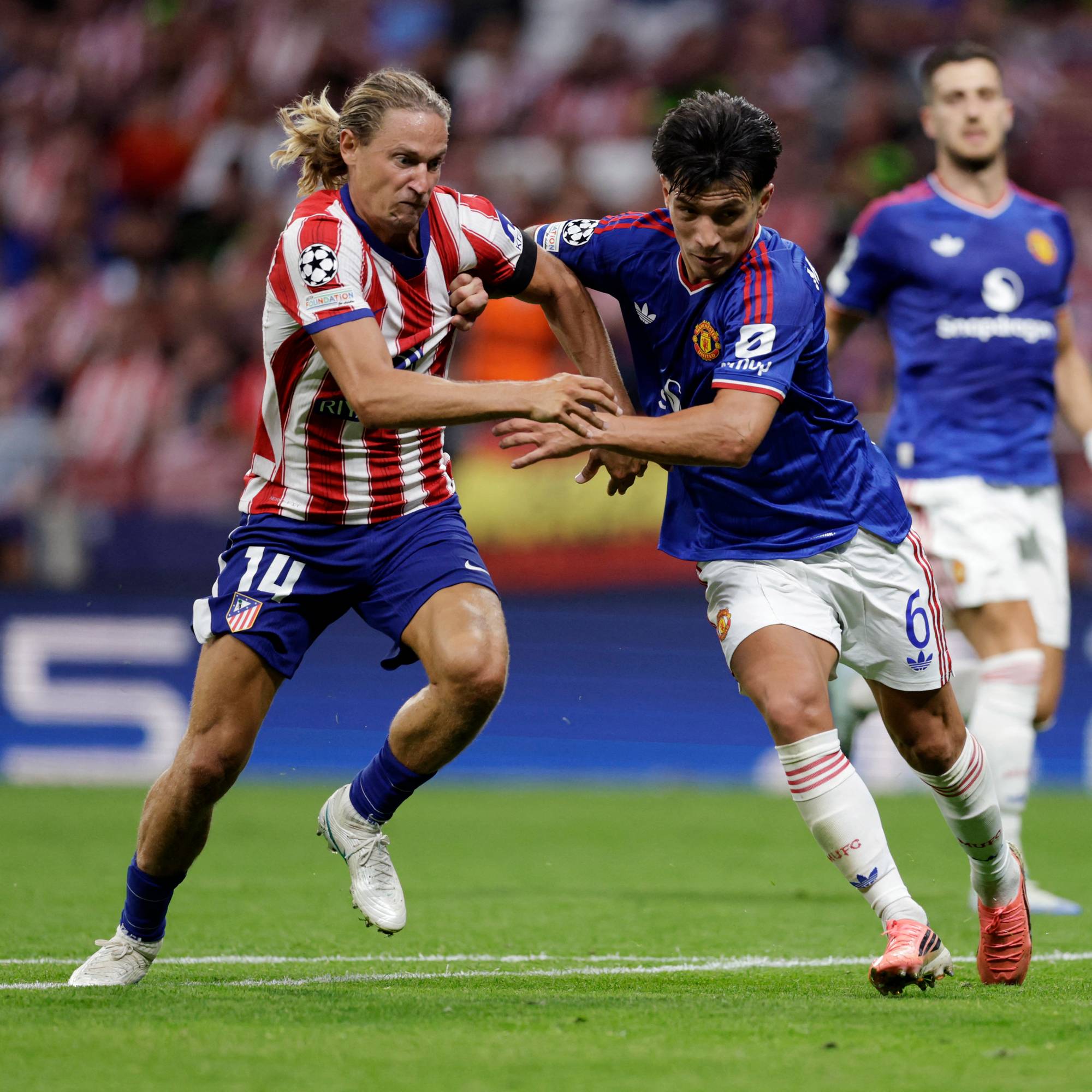 Fotballspillere fra Atlético Madrid og Manchester United kjemper om ballen på en gressbane. (Bildebeskrivelsen er laget av en KI-tjeneste)