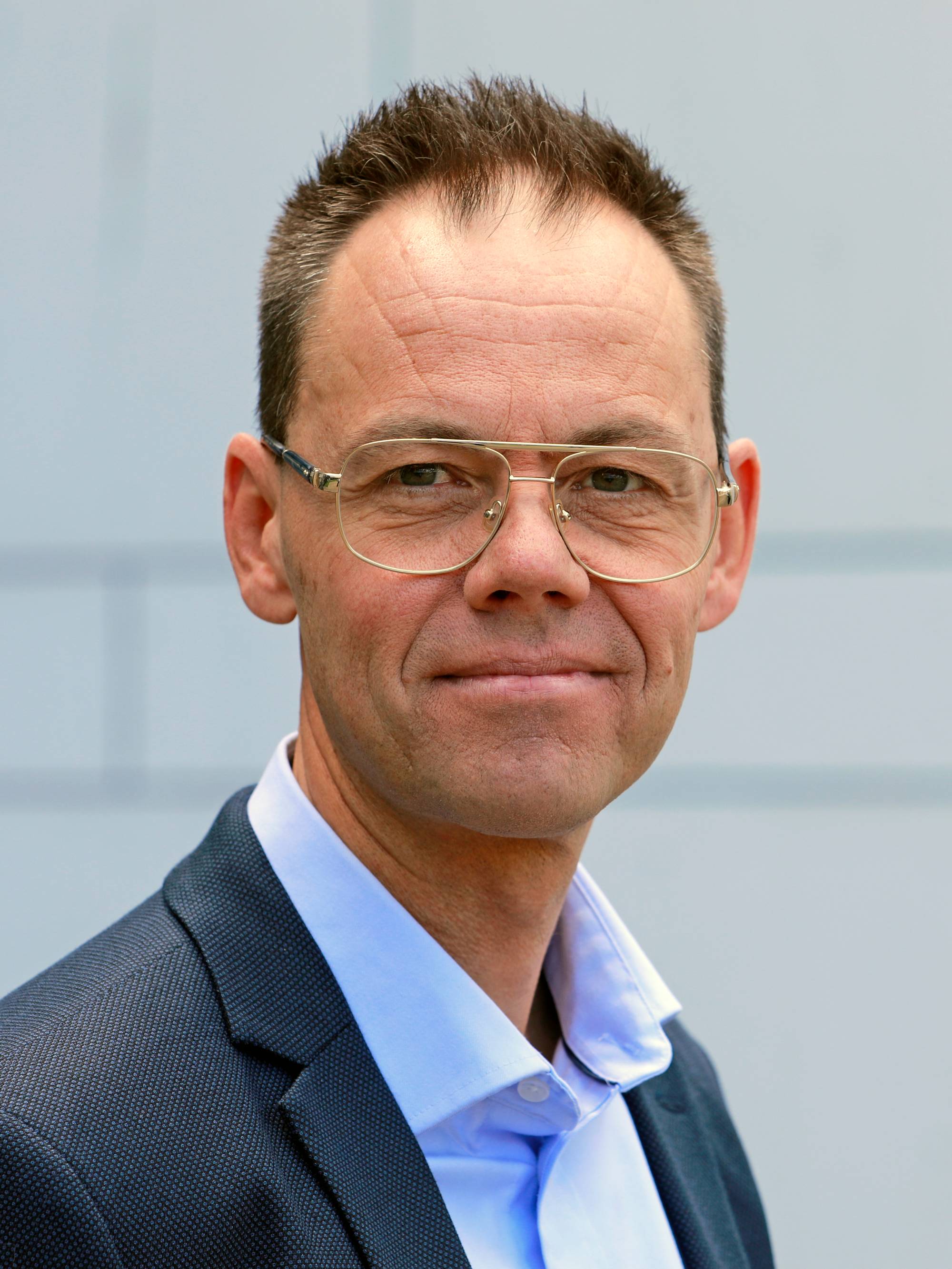 Magnus Frantzen Eidsvold, talsperson for Equinor ASA har mørk dress med blå skjorte, briller og kort brunt hår. Han står foran en hvit vegg og ser i kamera.