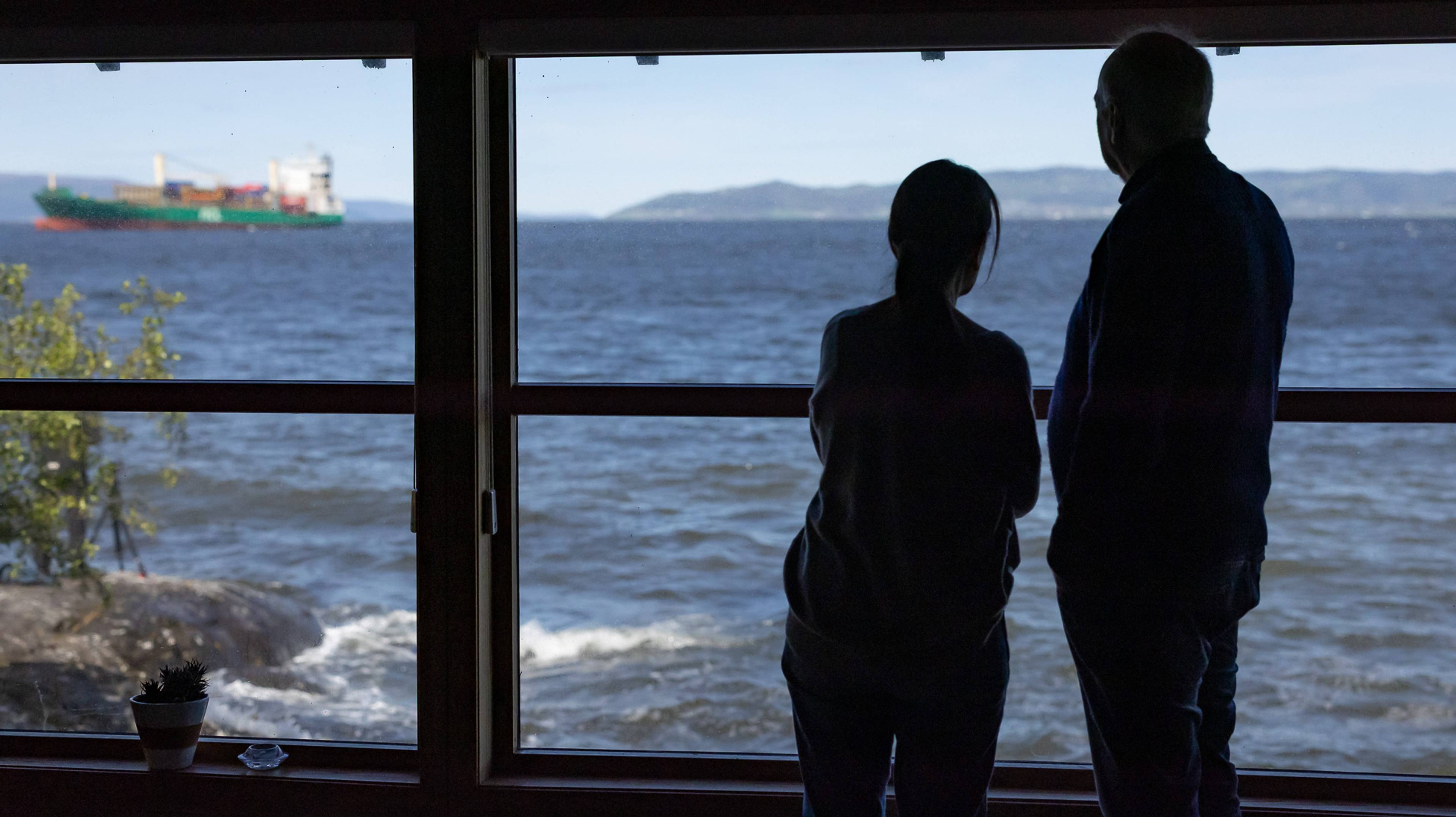 Joanne Fielder og Johan Helberg står i stuen og kikkar kontainerskipet som er ute i fjorden