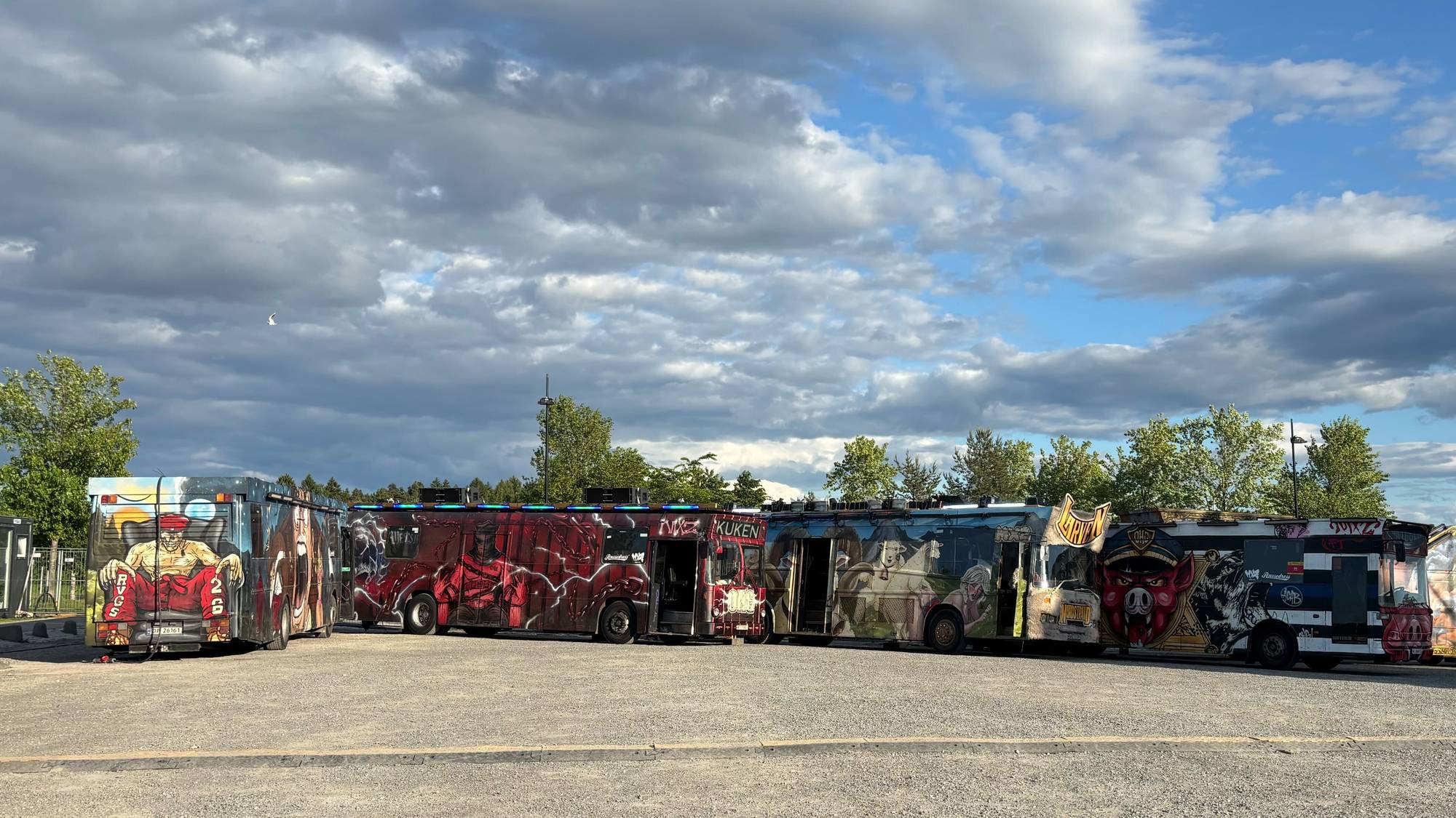 Russebusser står parkert på en parkeringsplass på Kadettangen i Bærum, det er kveldssol og skygger. 
