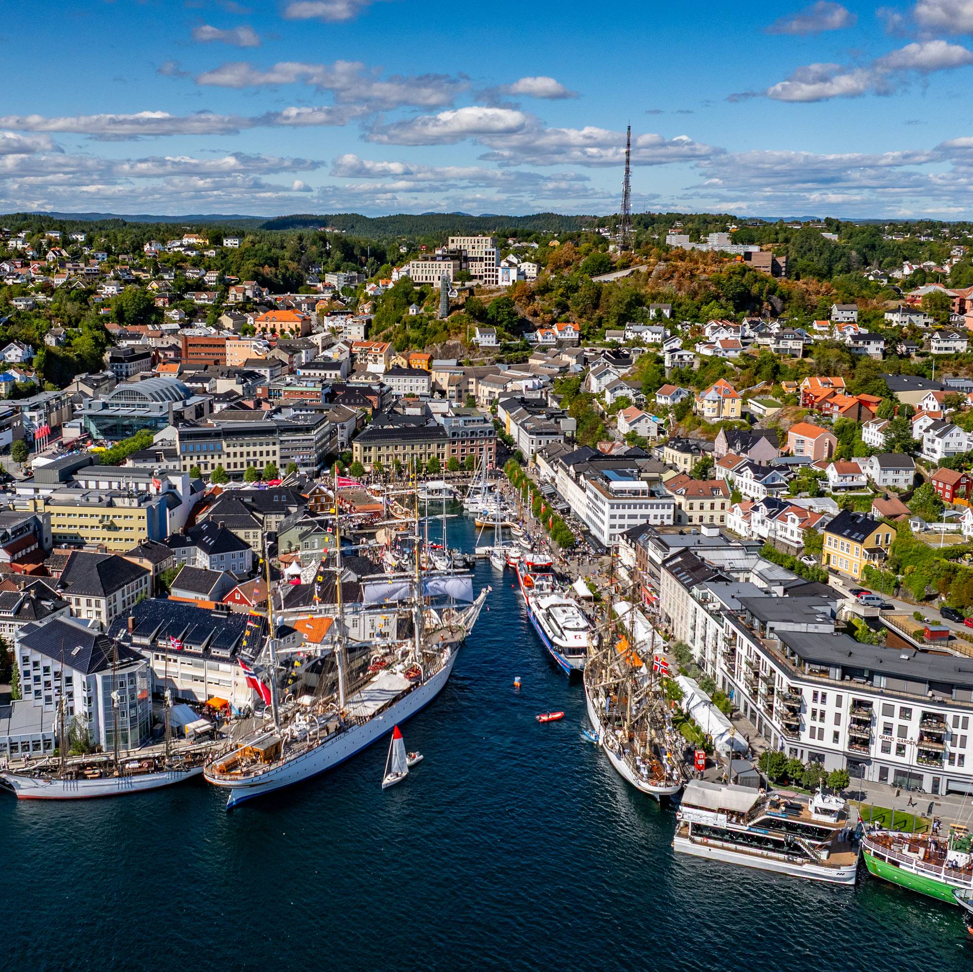 Flyfoto av Kristiansand sentrum med seilskip i havnen. (Bildebeskrivelsen er laget av en KI-tjeneste)