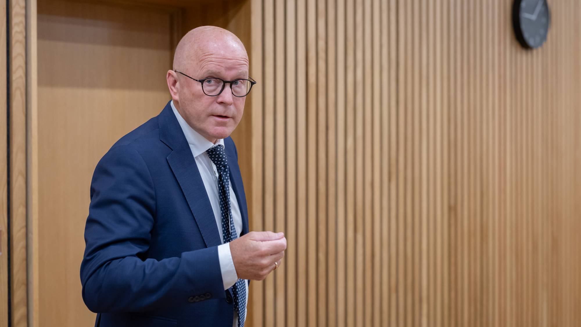 Statsadvokat Per Morten Schjetne er i en rettssal. Han står og snakker med noen før retten er satt. Han er iført dress og gjør en håndbevegelse og kikker ut av bildet