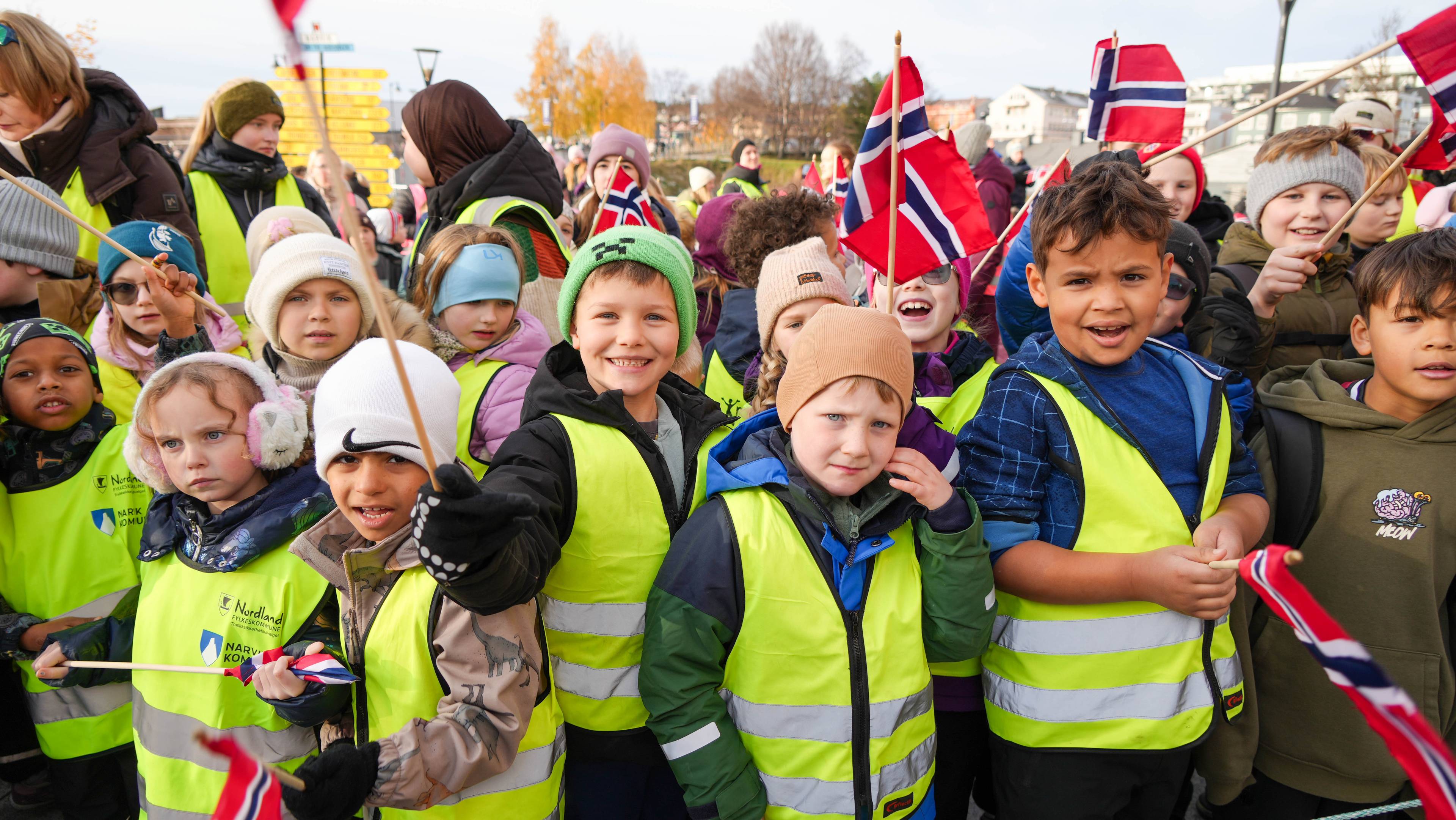 Barn med luer, jakker og refleksvester veiver med flagg