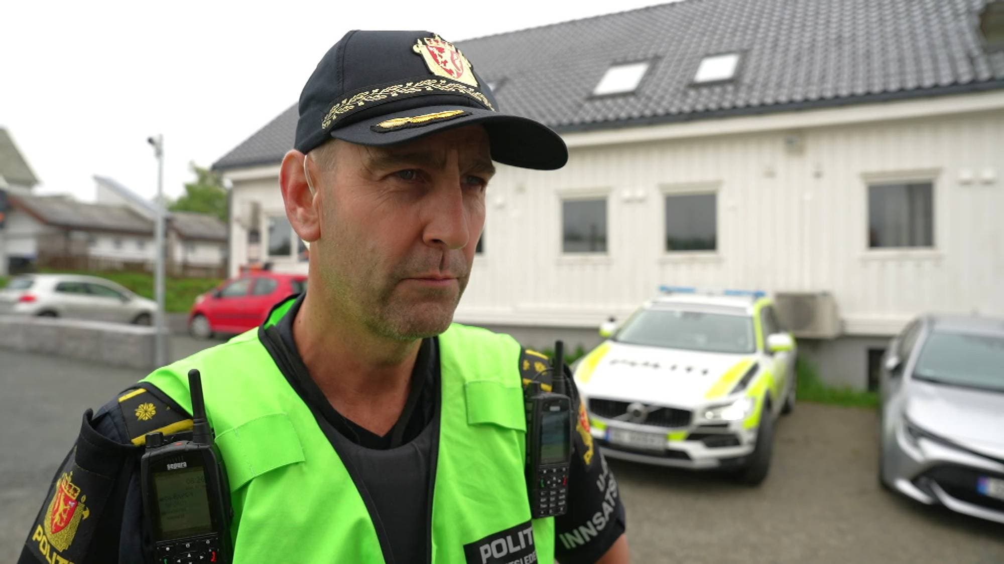 Politimann i uniform og grønn vest. 