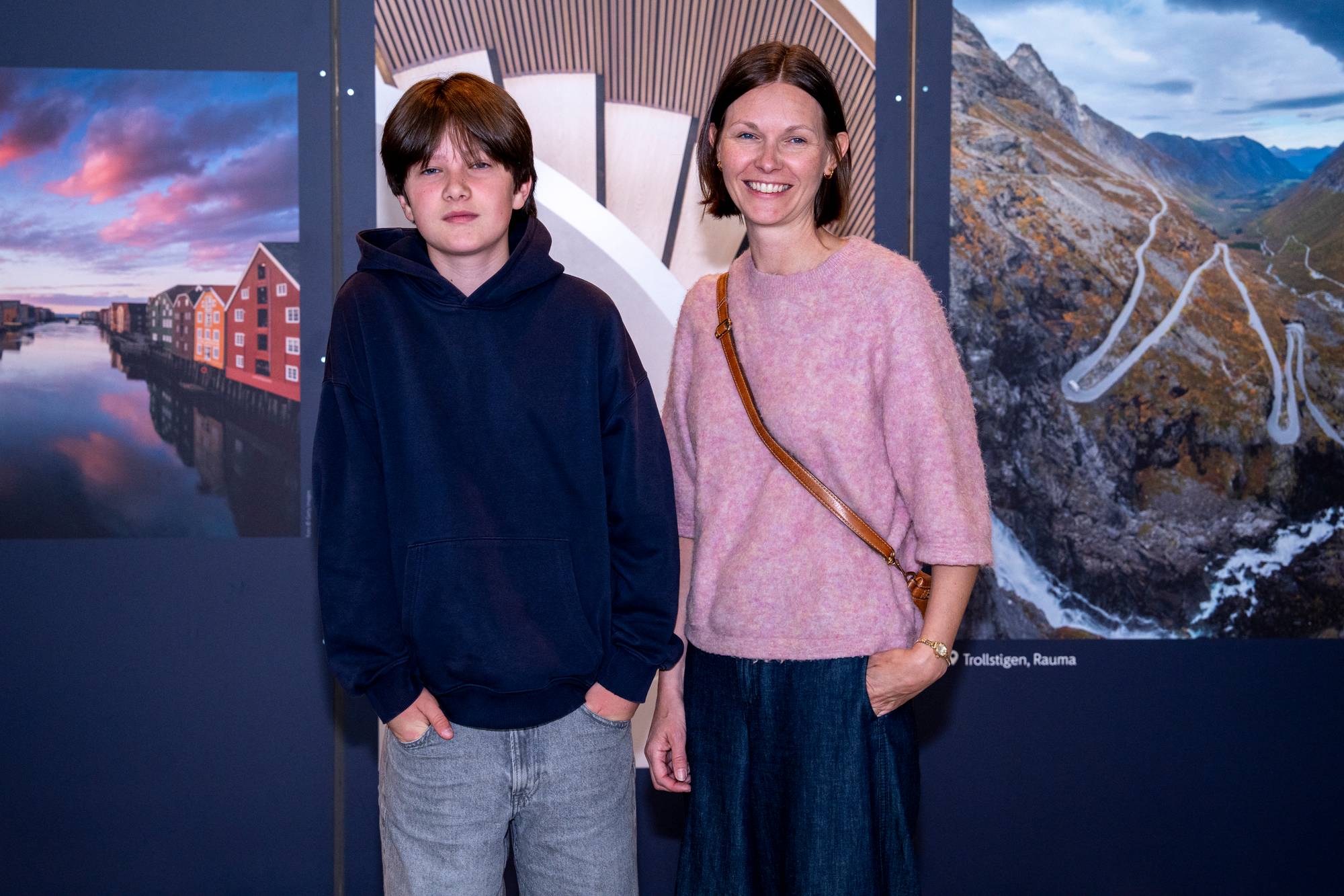 en gutt og en kvinne som står foran en vegg med turist-bilder