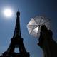 Gonzalo Fuentes / Reuters / NTB en person som holder en paraply ved siden eiffeltårnet