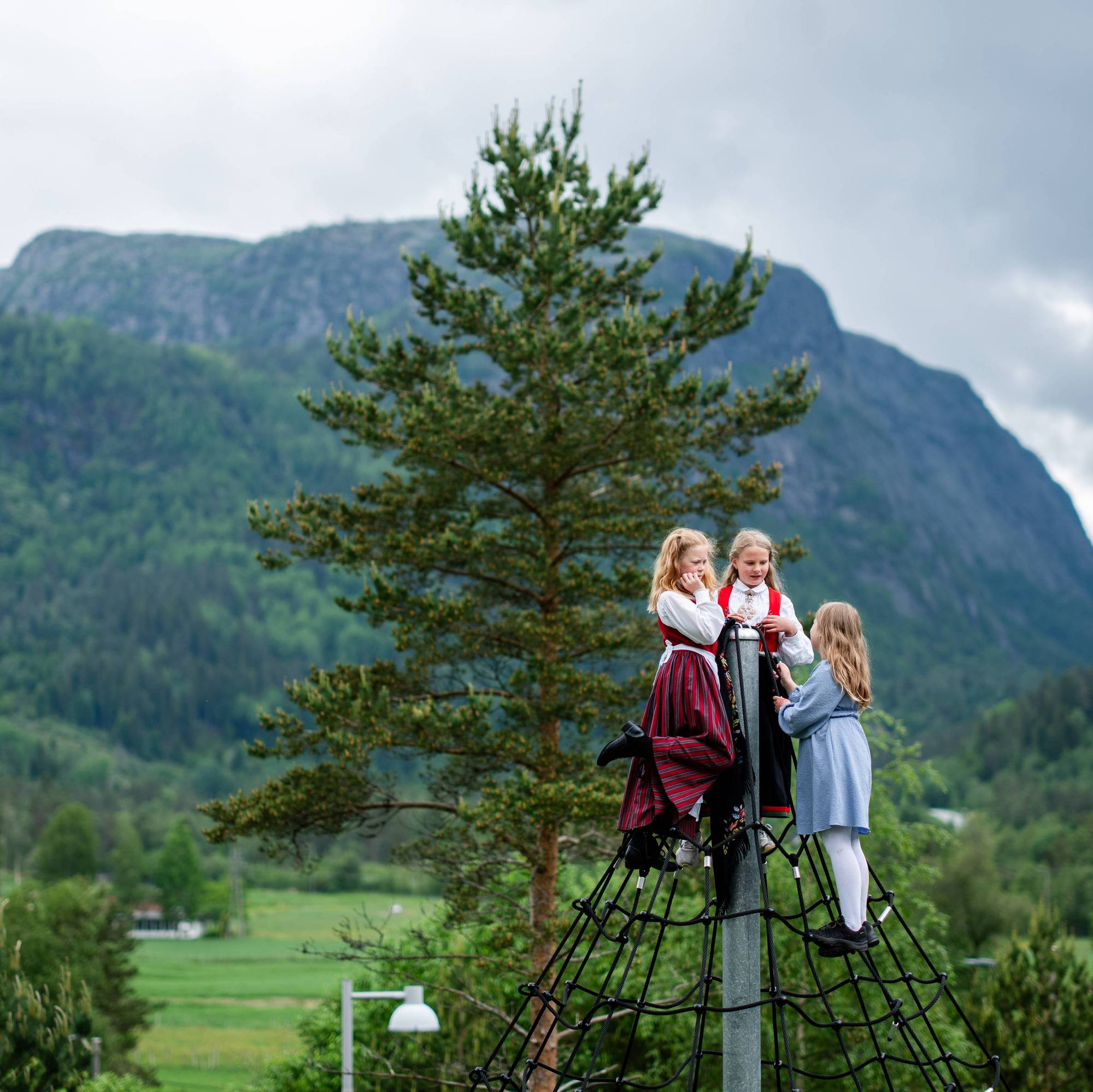 Tre jenter har klatret til toppen av et klatrestativ for å få et glimt av kongen i Åseral 27. mai 2024