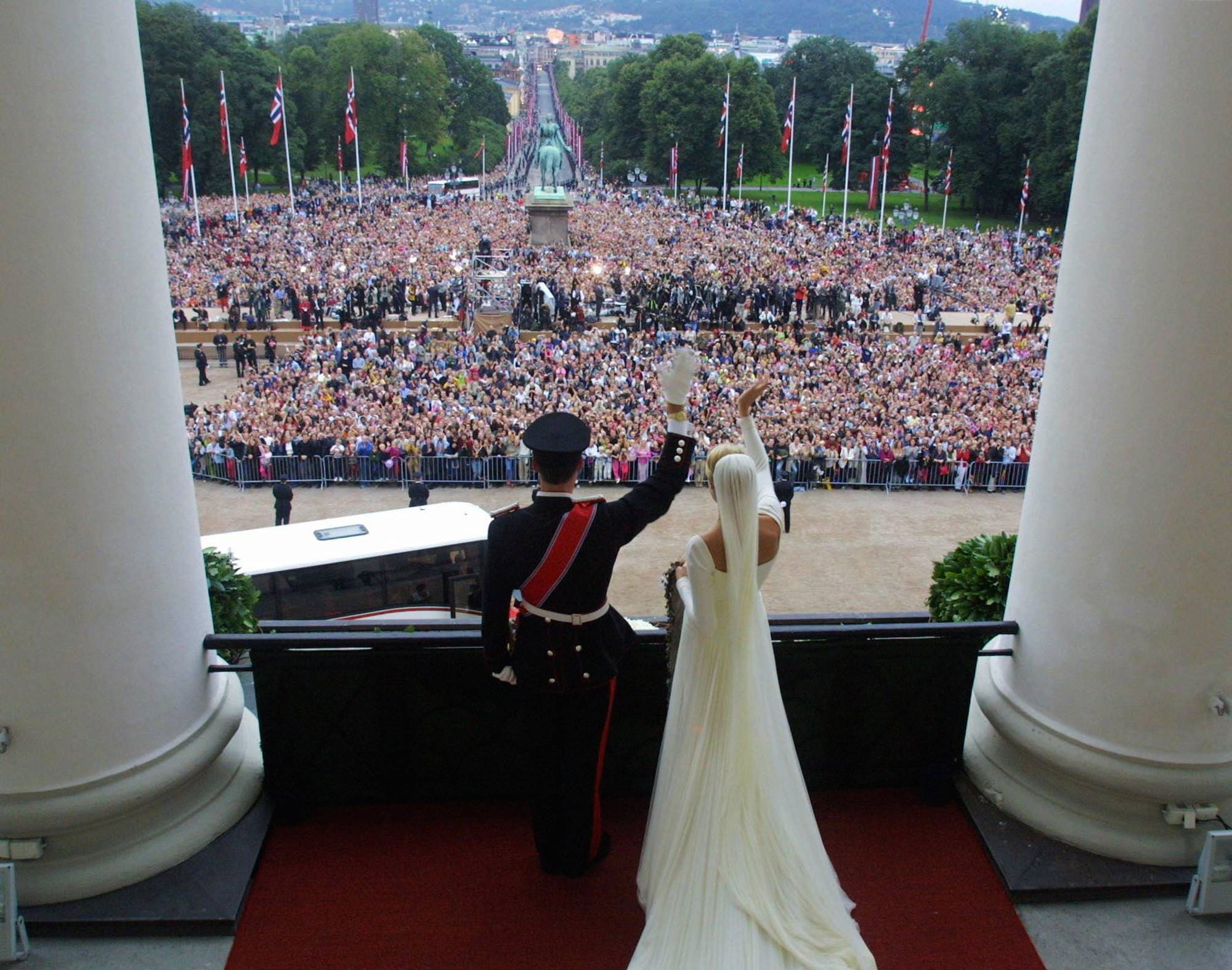 Kronprins Haakon og kronprinsesse Mette-Marit står på Slottsbalkongen og vinker til folkehavet på Slottsplassen etter at paret ble viet 25. august 2001