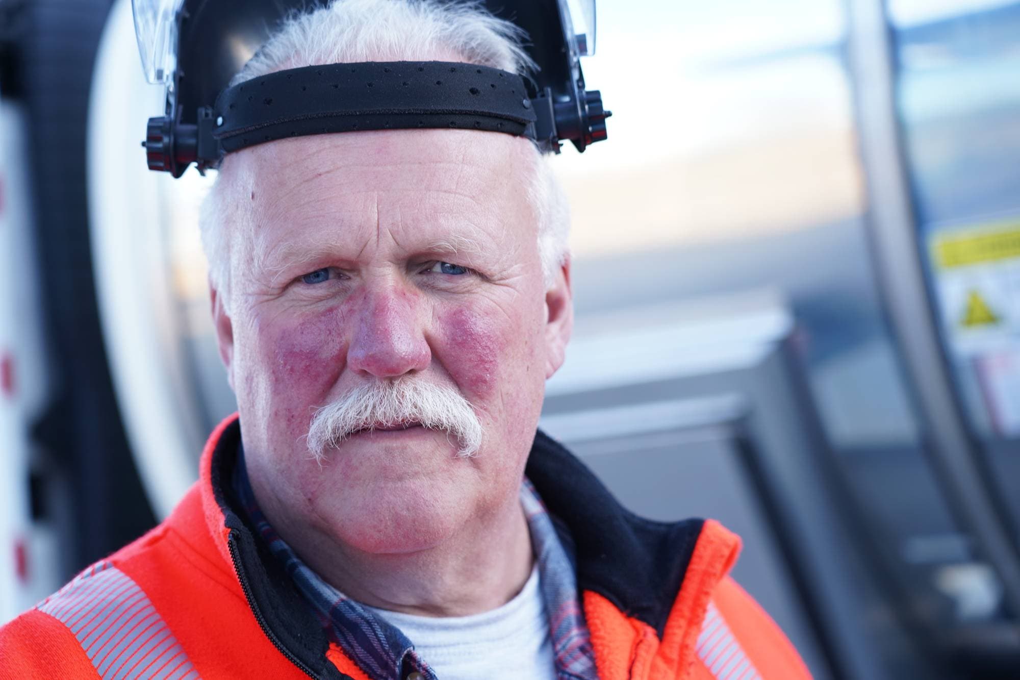 Ole Jørgen Østreng er sjåfør i Kværnhaugen Transport og kjører melketankbil for Tine. Her har han beskyttelsesmaske på hodet med visiret brettet opp. Når han fyller flytende biogass på bilen, må han bruke verneutstyr. Flytende biogass holder nemlig en temperatur på 160 minusgrader.