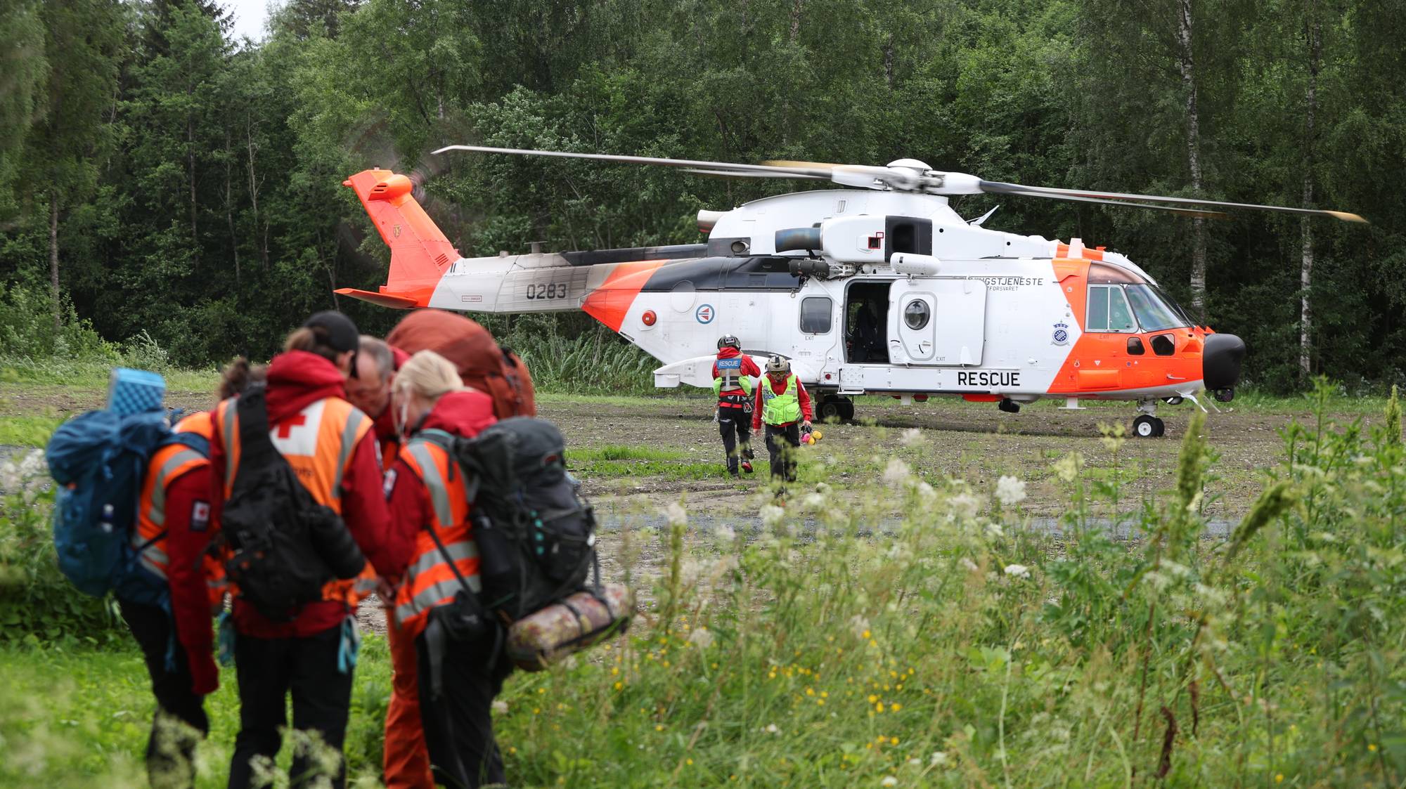 En gruppe mennesker foran et helikopter (Bildebeskrivelsen er laget av en KI-tjeneste)
