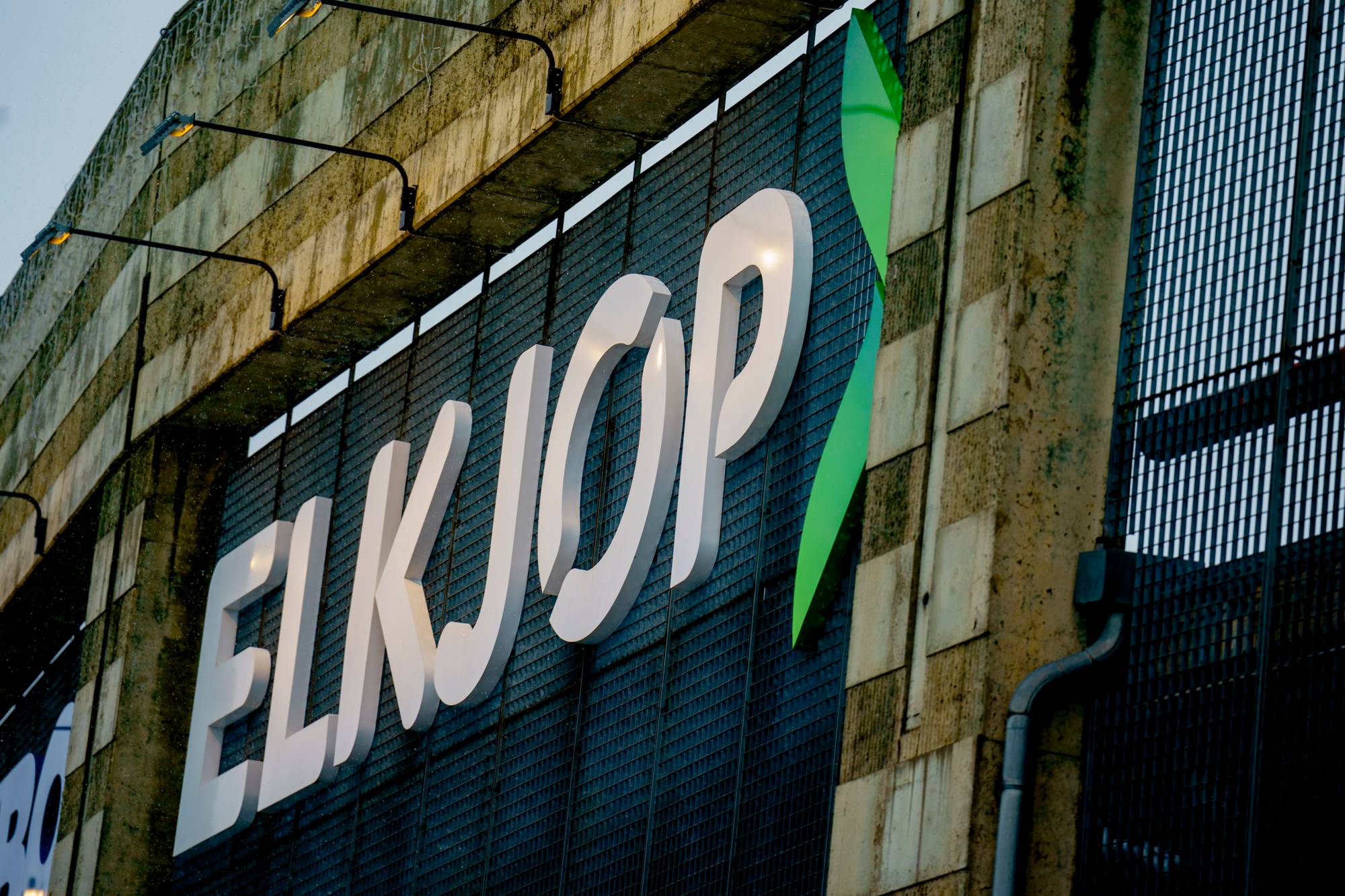 Elkjøp-logo i store, hvite bokstaver montert på en bygningsfasade. (Bildebeskrivelsen er laget av en KI-tjeneste)
