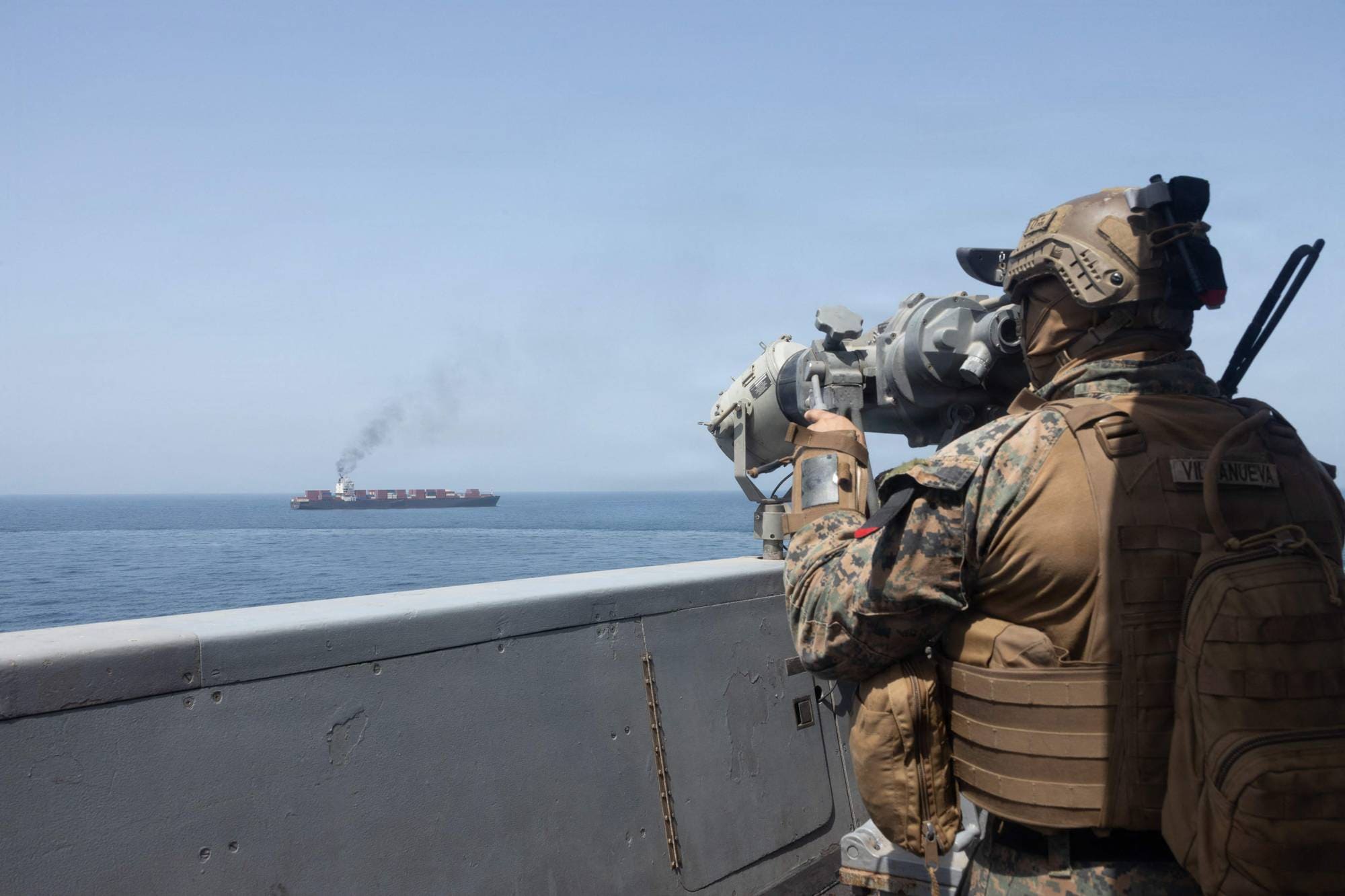 En soldat på skip som følger med på et tankskip i Hormuzstredet