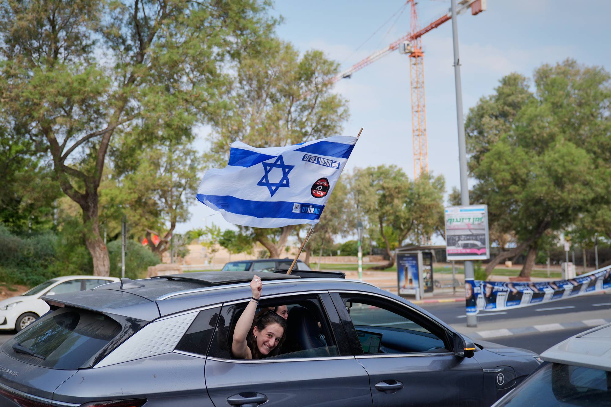 Kvinne holder et israelsk flagg ut av vinduet på en kjørende bil. (Bildebeskrivelsen er laget av en KI-tjeneste)