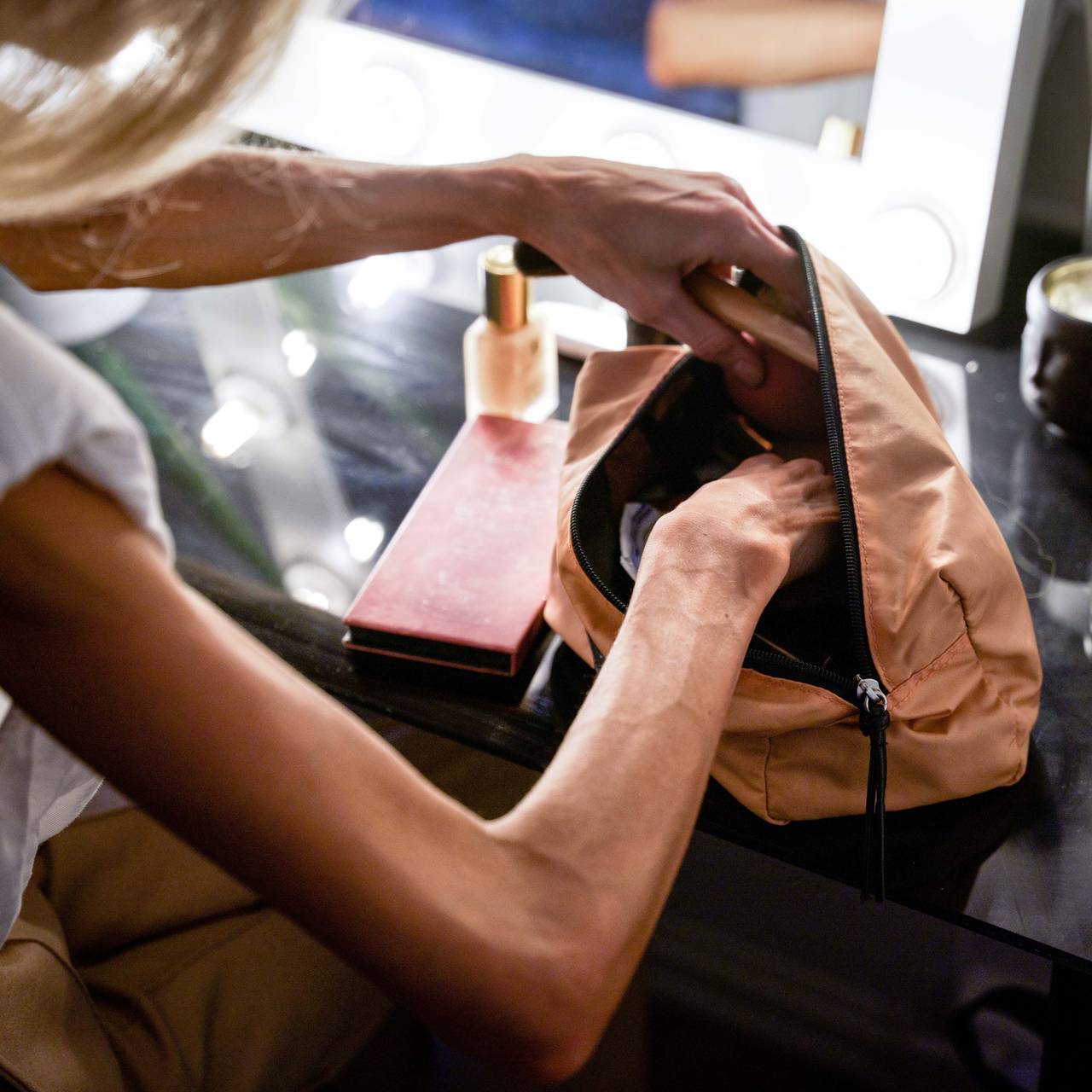 Nærbilde av armene til Caroline, som leter etter noe i sminkevesken