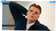 Mann ser til siden og har armen bak hodet.