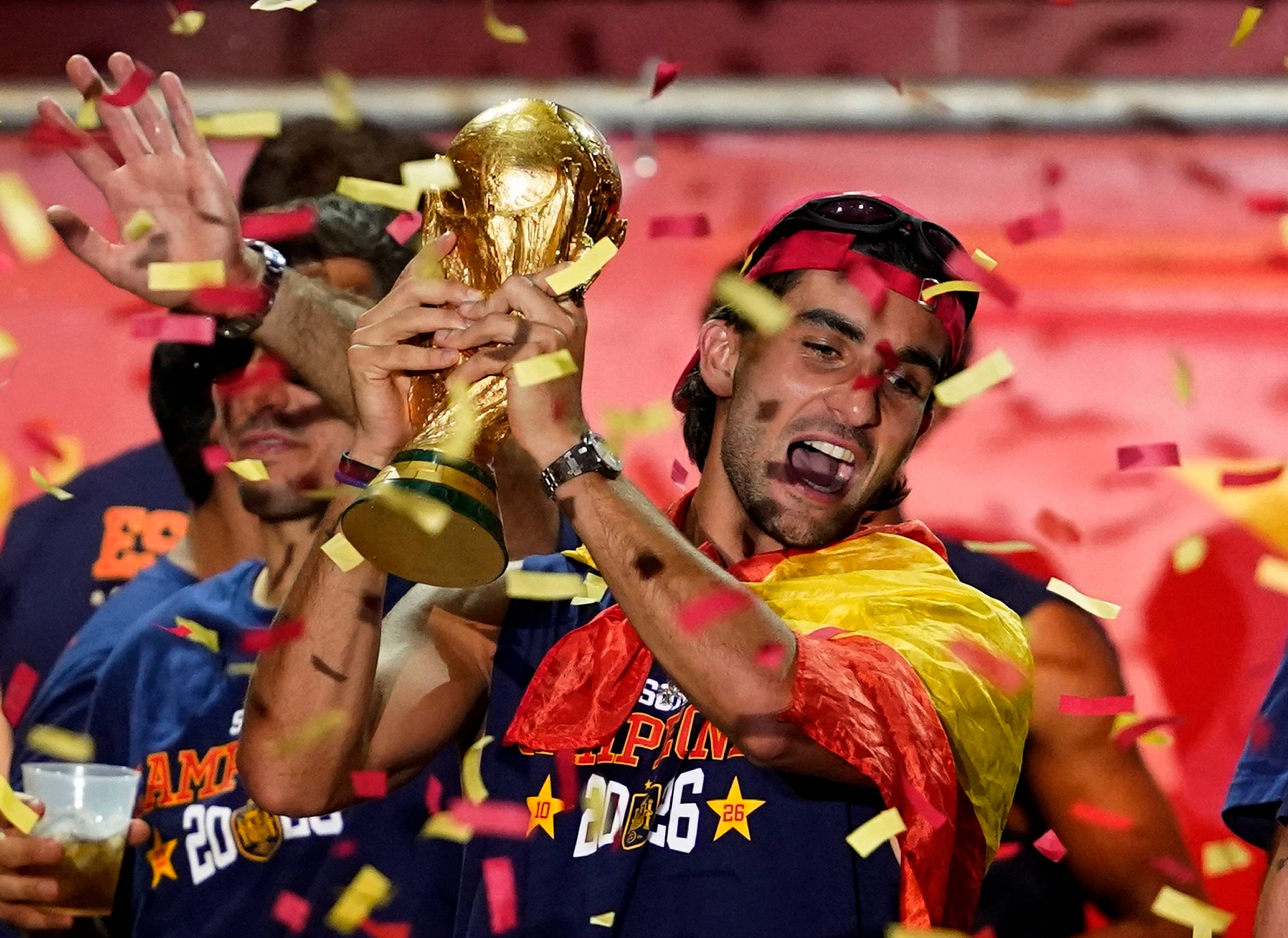 En mann ikledd spanske farger holder oppe en pokal og det er masse konfetti