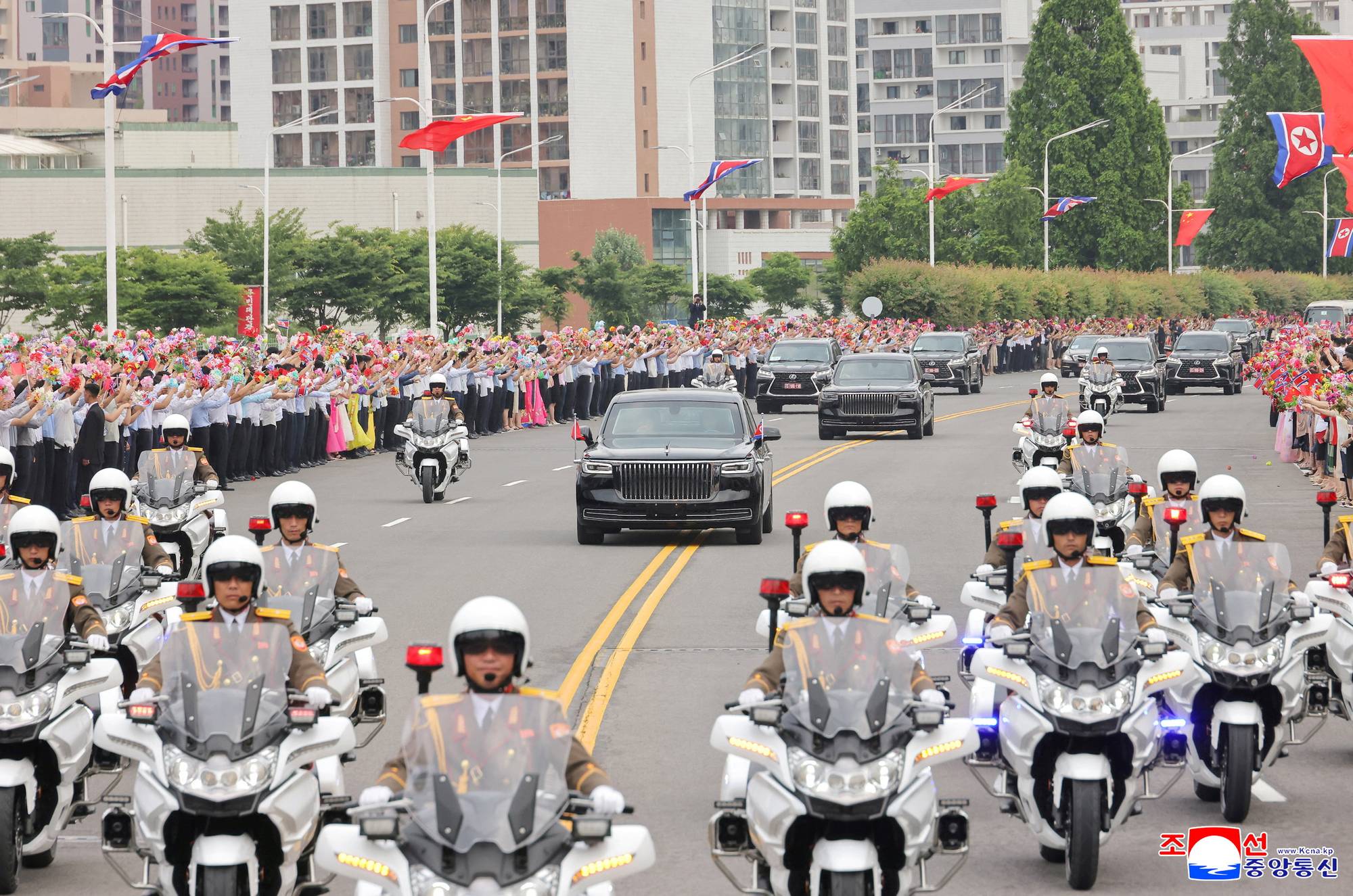 Publikum i Pyongyang vinker til Kinas president, Xi Jinping, som kjører forbi i bilkortesje. 