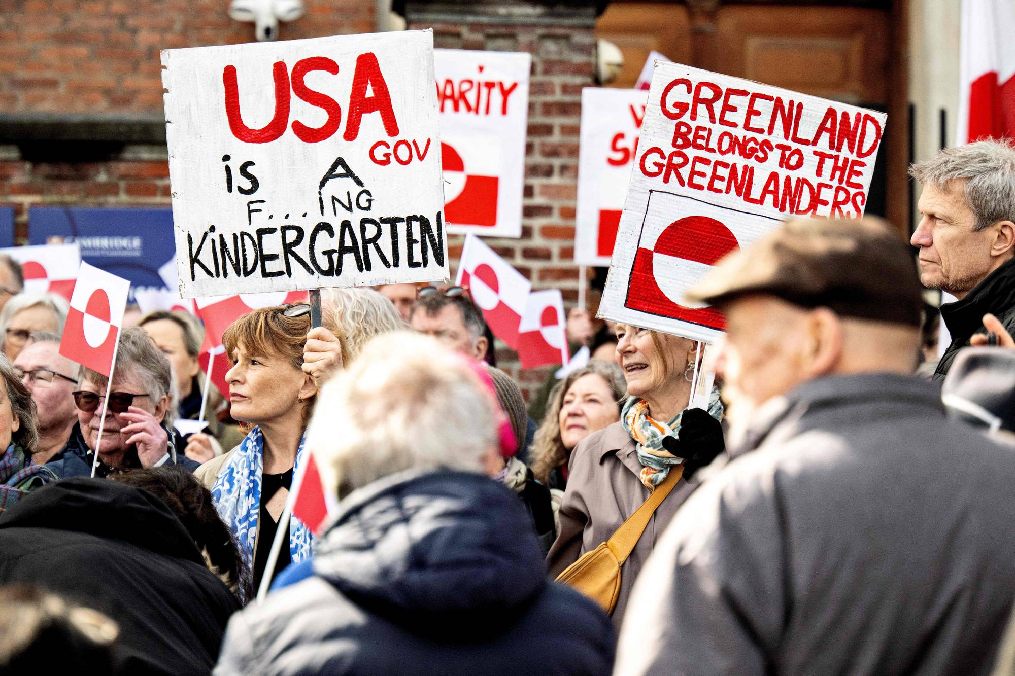 Demonstrasjoner mot USA på Grønland - en folkemengde med plakater hvor det står blant annet Greenland belongs to the Greenlanders