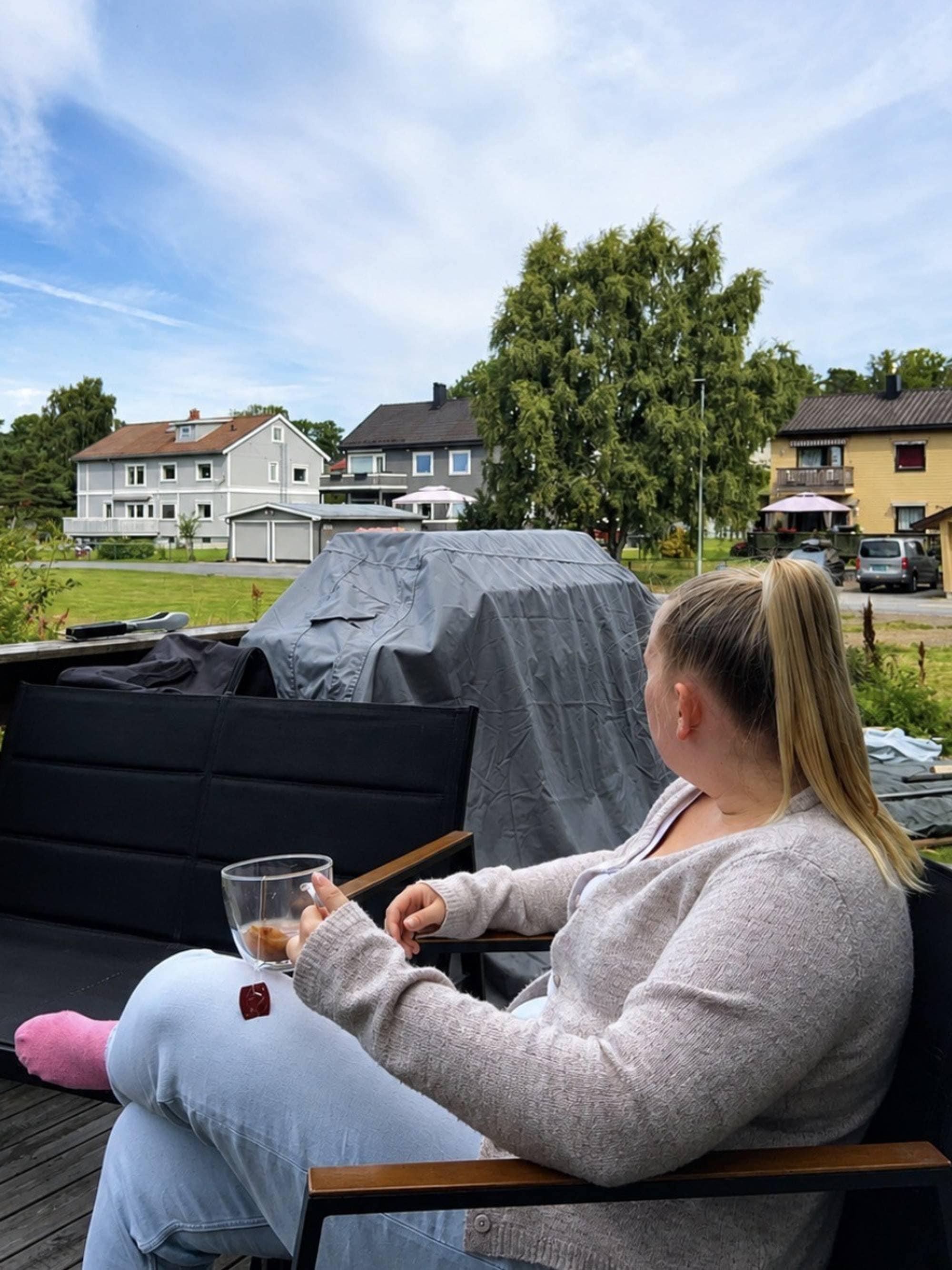 Kvinne sitter på veranda med kaffe