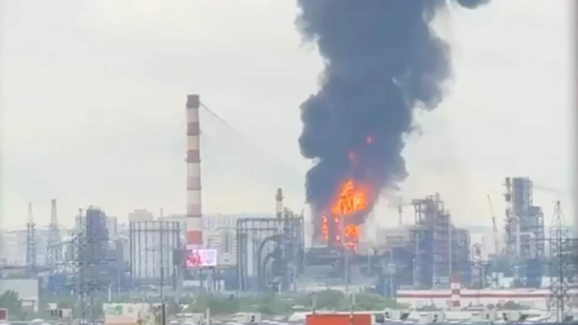 Stor svart røyk stiger fra et industriområde der det brenner i en fabrikk. Flammene er synlige midt i en bygning i anlegget. Andre høye strukturer som piper og tårn er synlige. (Bildebeskrivelsen er laget av en KI-tjeneste)