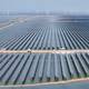 Foto: AFP Bilde av en stor solcellepark med rader av solcellepaneler i vann. I bakgrunnen er det vindturbiner. Noen kjøretøy er synlige ved panelene. (Bildebeskrivelsen er laget av en KI-tjeneste)