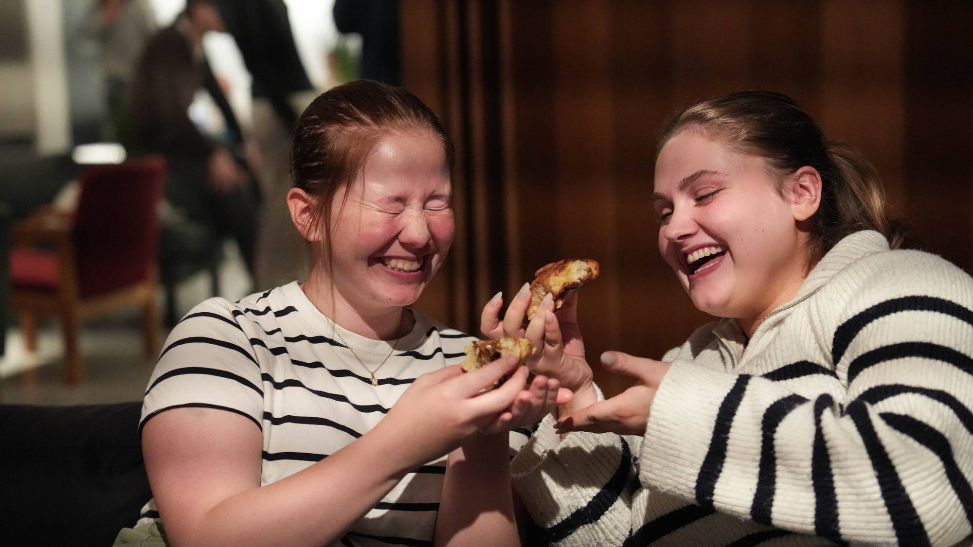 To unge kvinner som baker boller og koser seg på folkehøgskole.