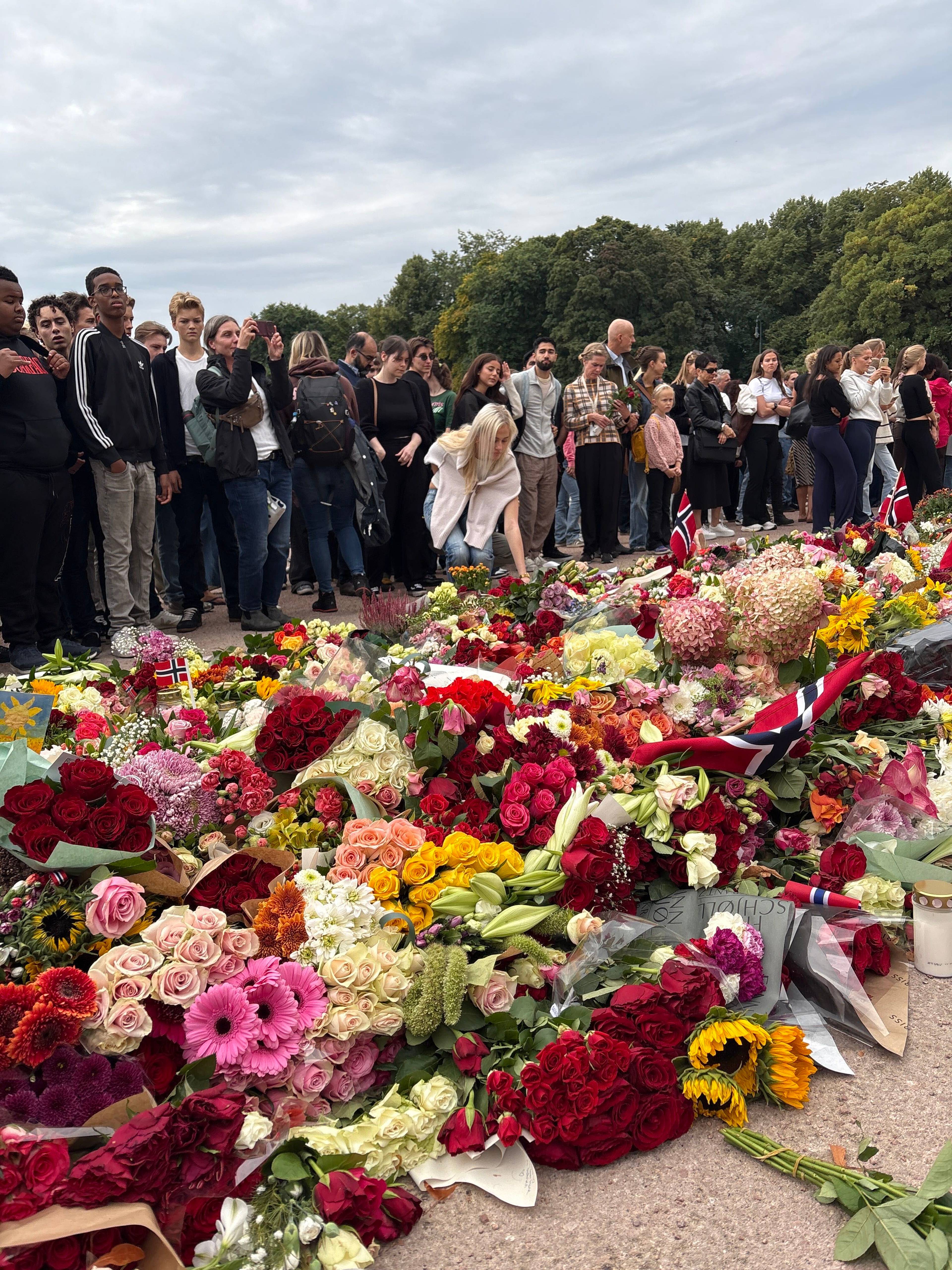 Folk samles og legger ned blomster på Slottsplassen