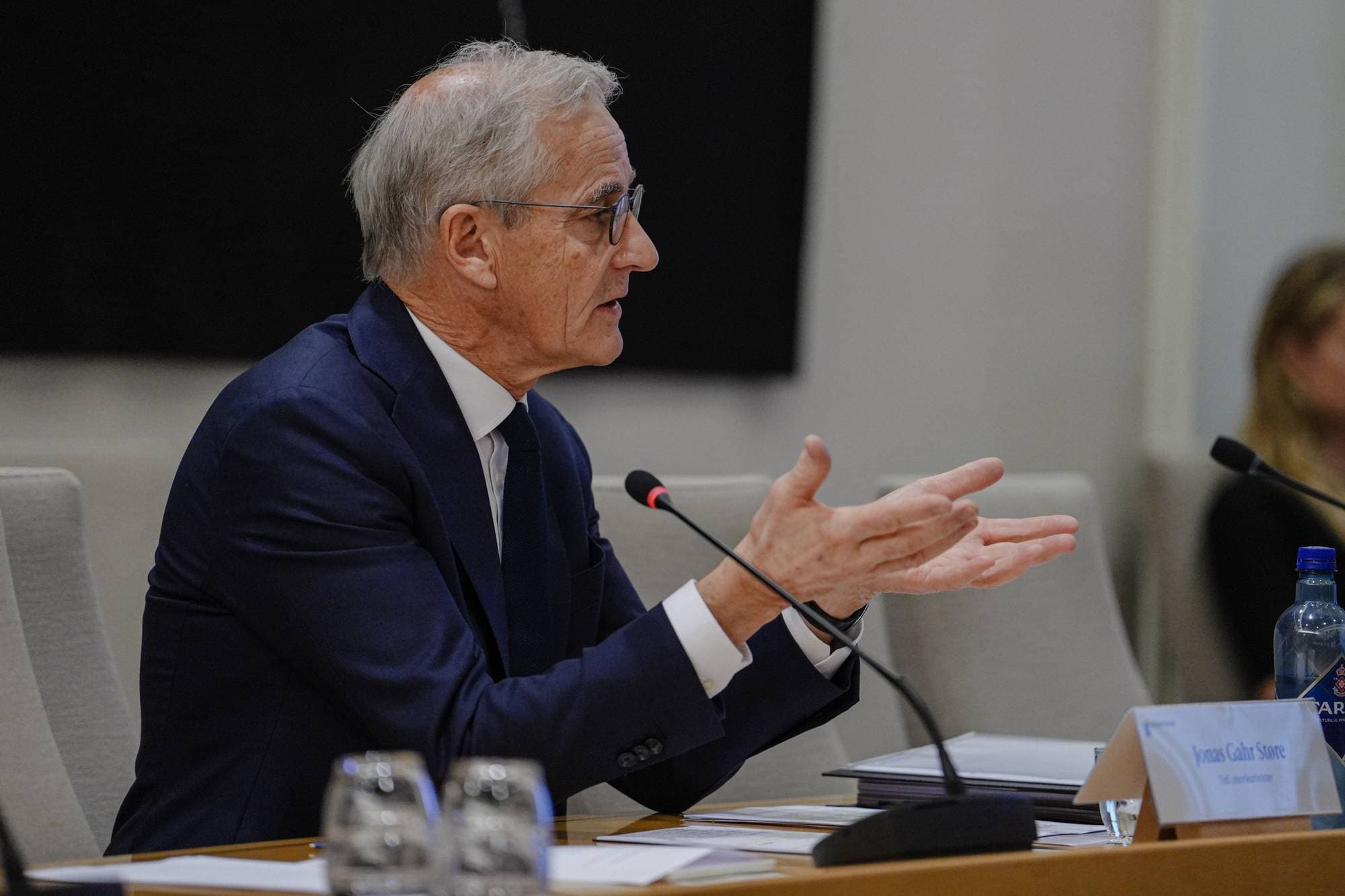 Statsminister Jonas Gahr Støre sitter ved et møtebord og snakker med hendene. (Bildebeskrivelsen er laget av en KI-tjeneste)