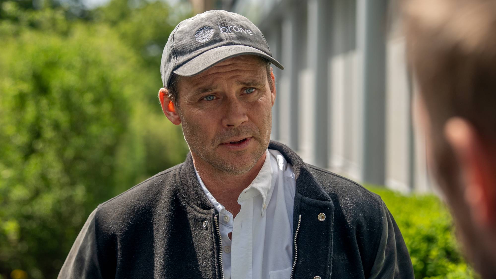 En mann står uten med en blå caps