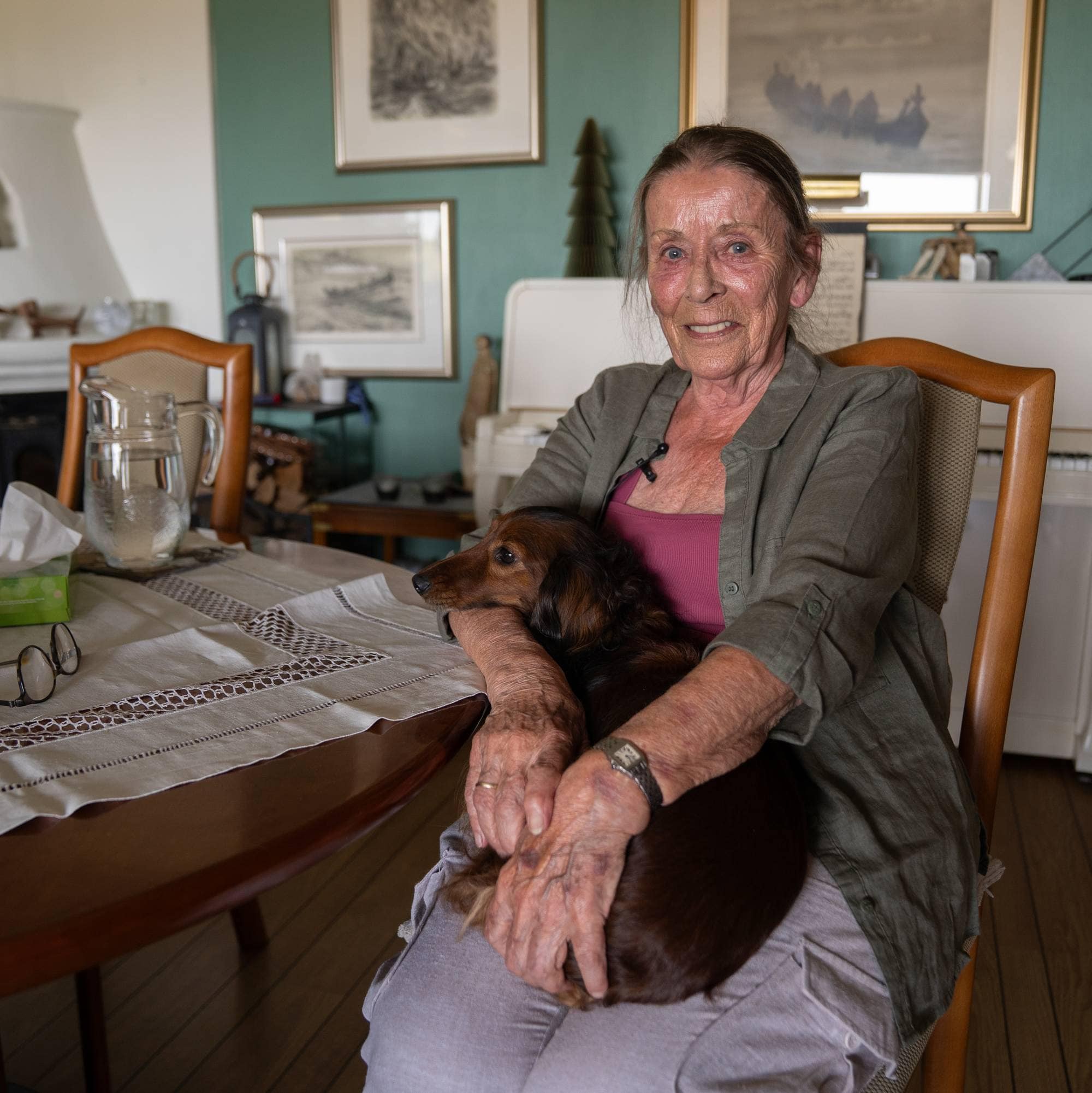 Marit Syversen sitter i stuen sin med Pippa, en brun, langhåret dvergdachs på fanget. 