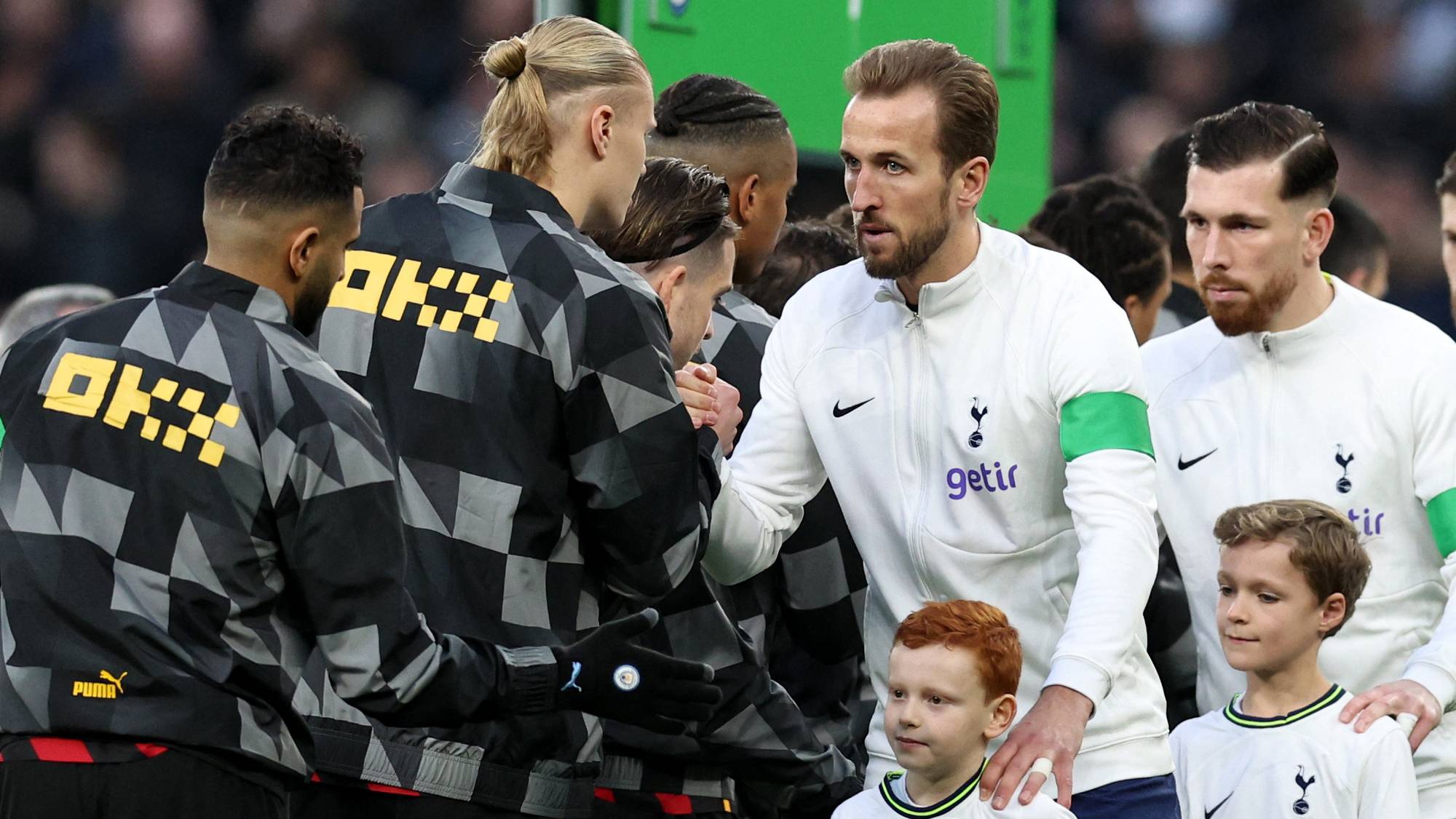 Erling Braut Haaland og Harry Kane håndhilser før en fotballkamp på banen. (Bildebeskrivelsen er laget av en KI-tjeneste)