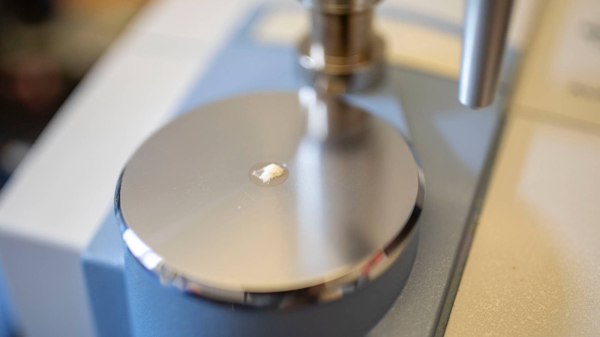 En hvit pulverprøve ligger på en metallplate under et instrument. Bildet er tatt nært. Det er ingen personer synlige i bildet. (Bildebeskrivelsen er laget av en KI-tjeneste)