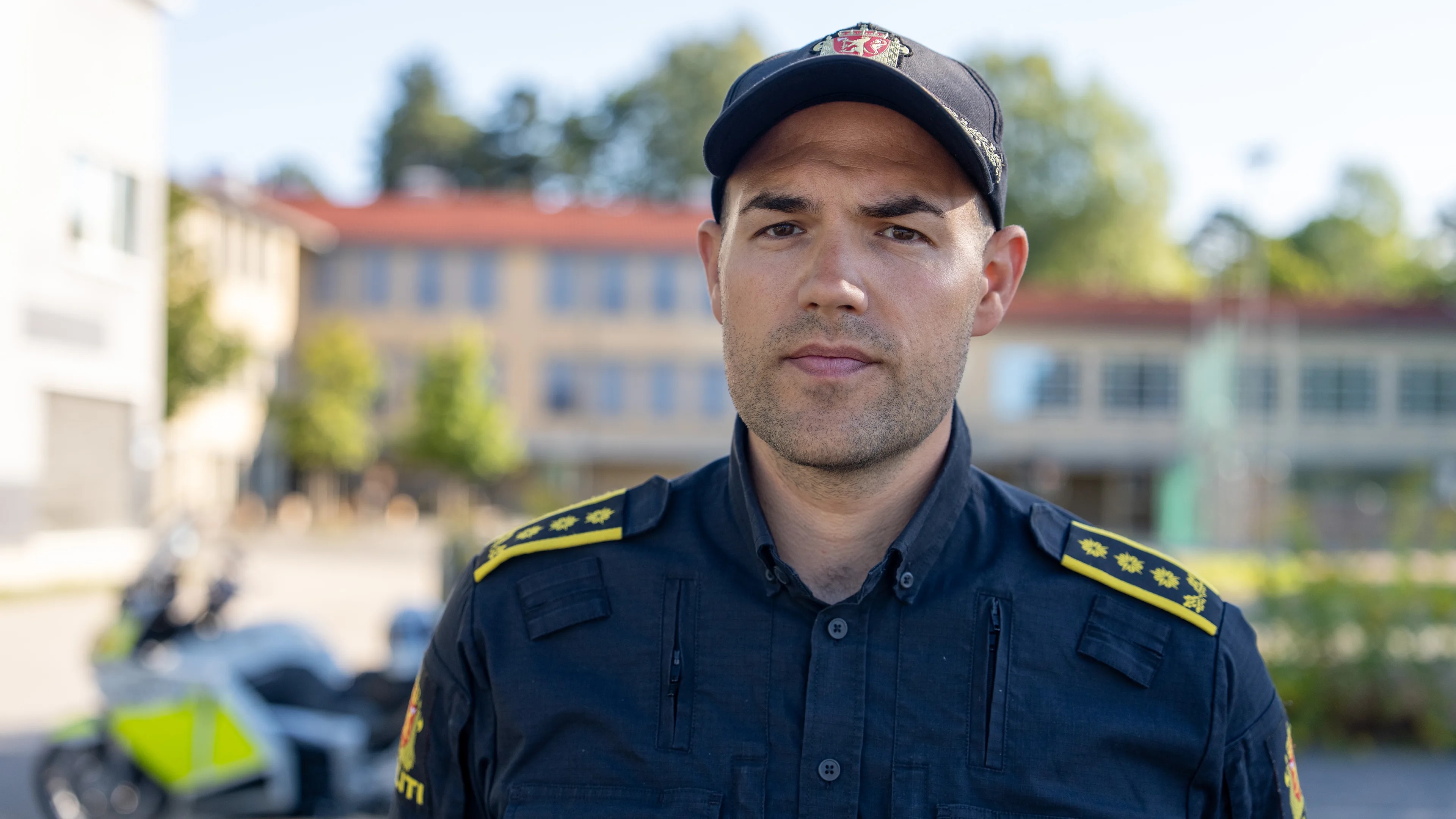 Mann i politiuniform står foran skoe og med motorsykkel i bakgrunnen.