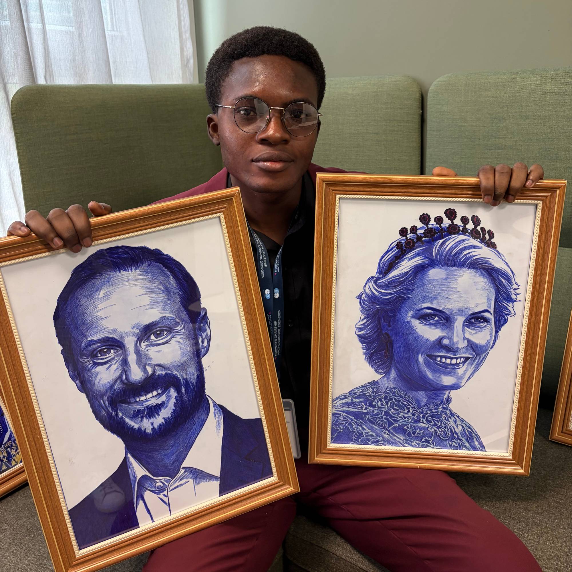 Ein ung mann held opp to innramma portrett av Kong Haakon og Dronning Mette-Marit.