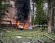 STATE EMERGENCY SERVICE OF UKRAINE / Handout,NTB Brannmannskaper slukker en bil som brenner kraftig. Bilen står parkert i et grønt område med trær og vegetasjon. En bygning er synlig i bakgrunnen. Flere brannslanger ligger på bakken, og det er mye røyk i luften. (Bildebeskrivelsen er laget av en KI-tjeneste)