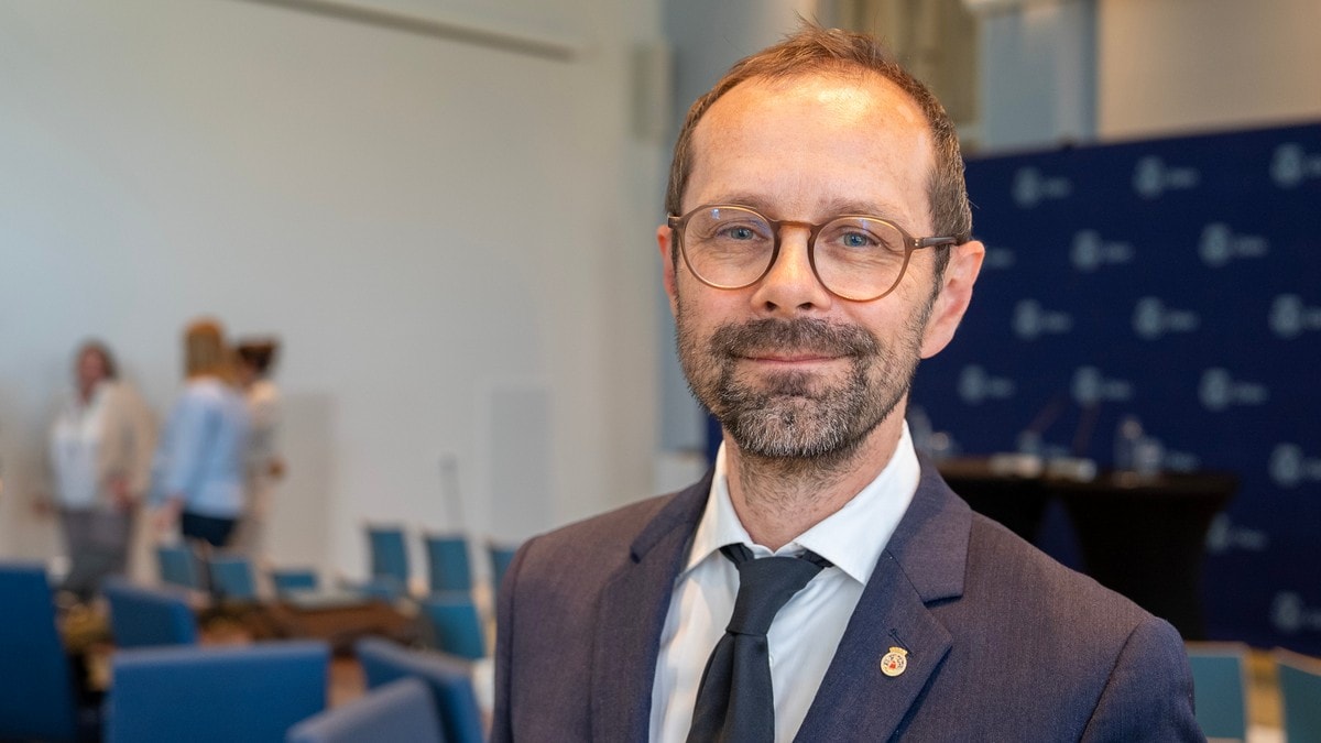 Mann med briller og dress i et møterom. Bakgrunnen viser deltakere og en blå logo-vegg. (Bildebeskrivelsen er laget av en KI-tjeneste) FOTO: Bård Nafstad/NRK Mann med briller og dress i et møterom. Bakgrunnen viser deltakere og en blå logo-vegg. (Bildebeskrivelsen er laget av en KI-tjeneste) FOTO: Bård Nafstad/NRK
