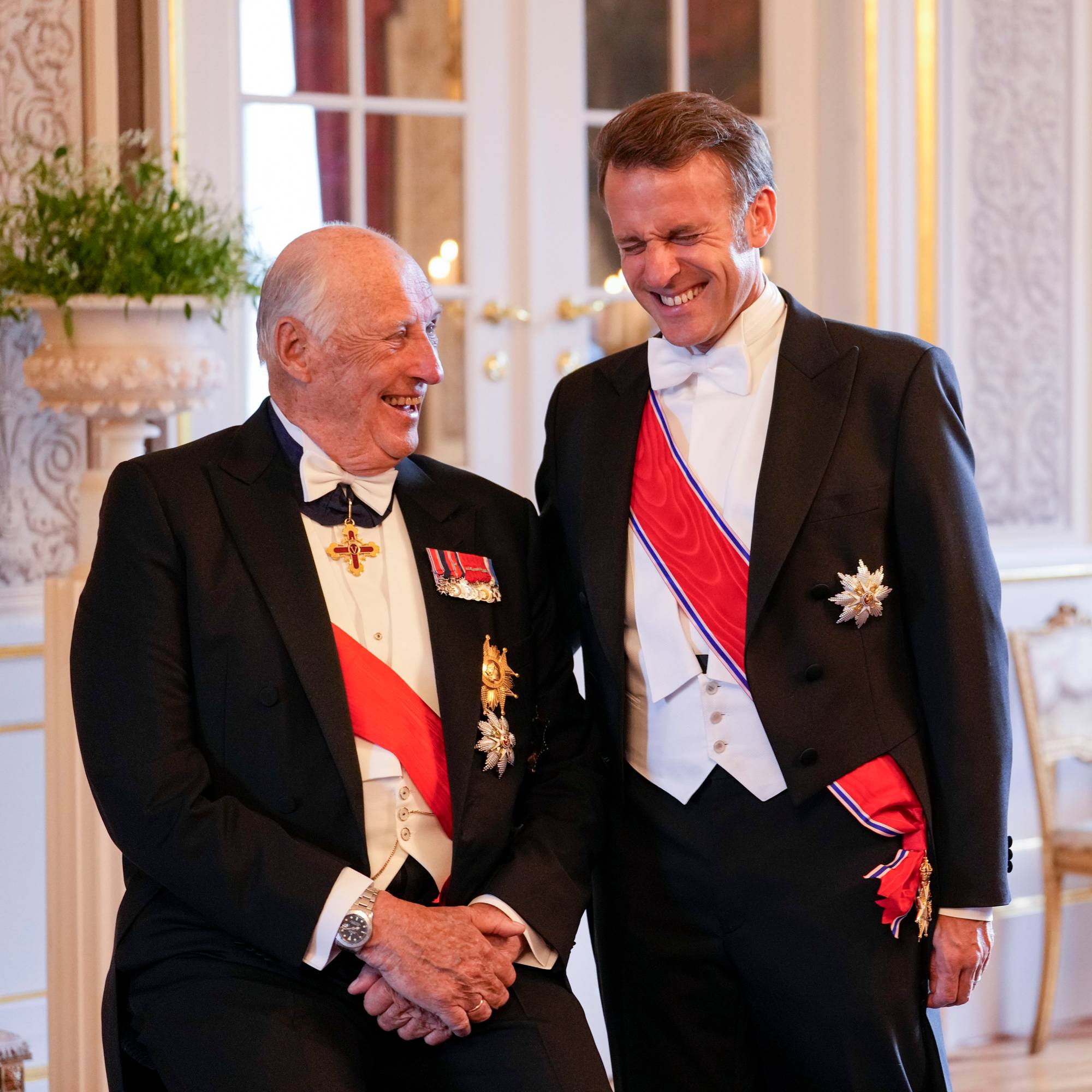 Kong Harald og Frankrikes president Emmanuel Macron ler sammen i gallaantrekk på Slottet. (Bildebeskrivelsen er laget av en KI-tjeneste)