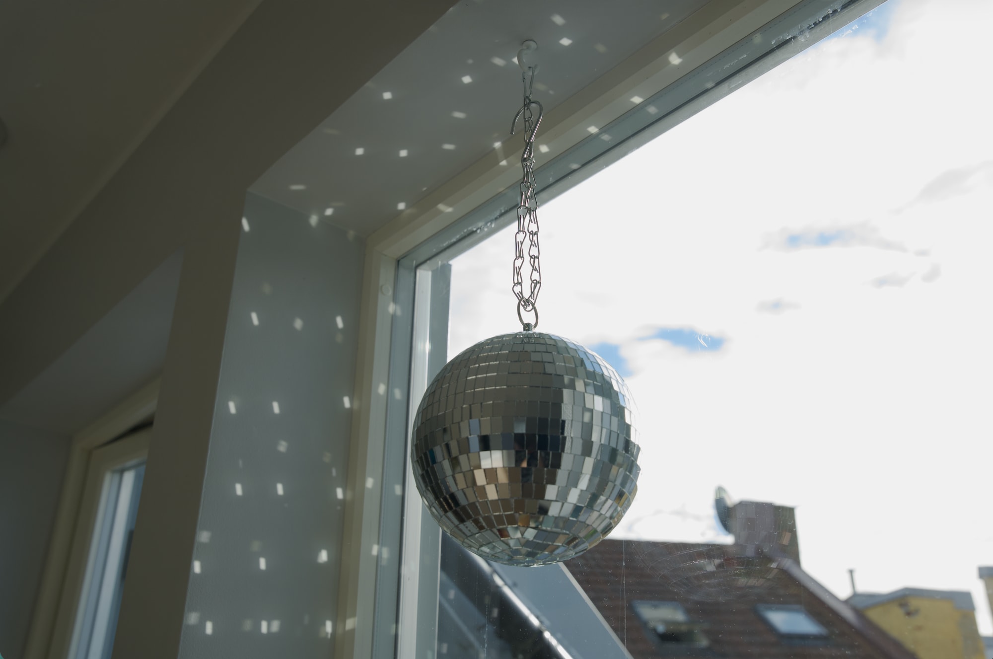 En liten discokule henger ned fra vinduskarmen i kollektivet. På veggen ser man refleksjonene av discokulen. 