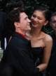 THOMAS COEX / AFP,NTB Skuespillerne Tom Holland og Zendaya smiler til hverandre. De er i en utendørs setting med andre personer synlig i bakgrunnen. Holland er ikledd en svart jakke over en rød skjorte, mens Zendaya bærer en stroppeløs svart kjole. (Bildebeskrivelsen er laget av en KI-tjeneste)