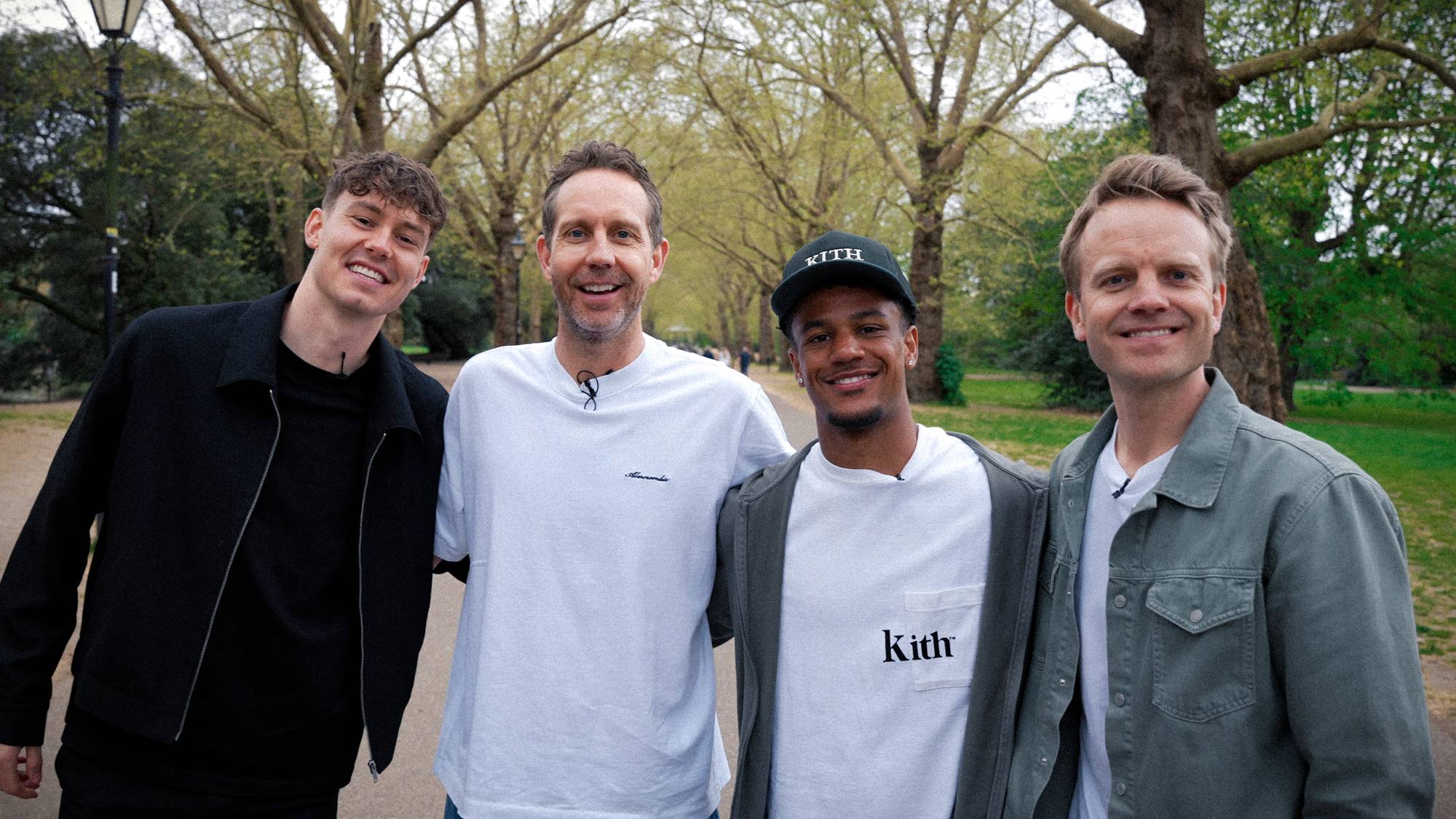 Fire menn holder rundt hverandre og ser i kamera. 