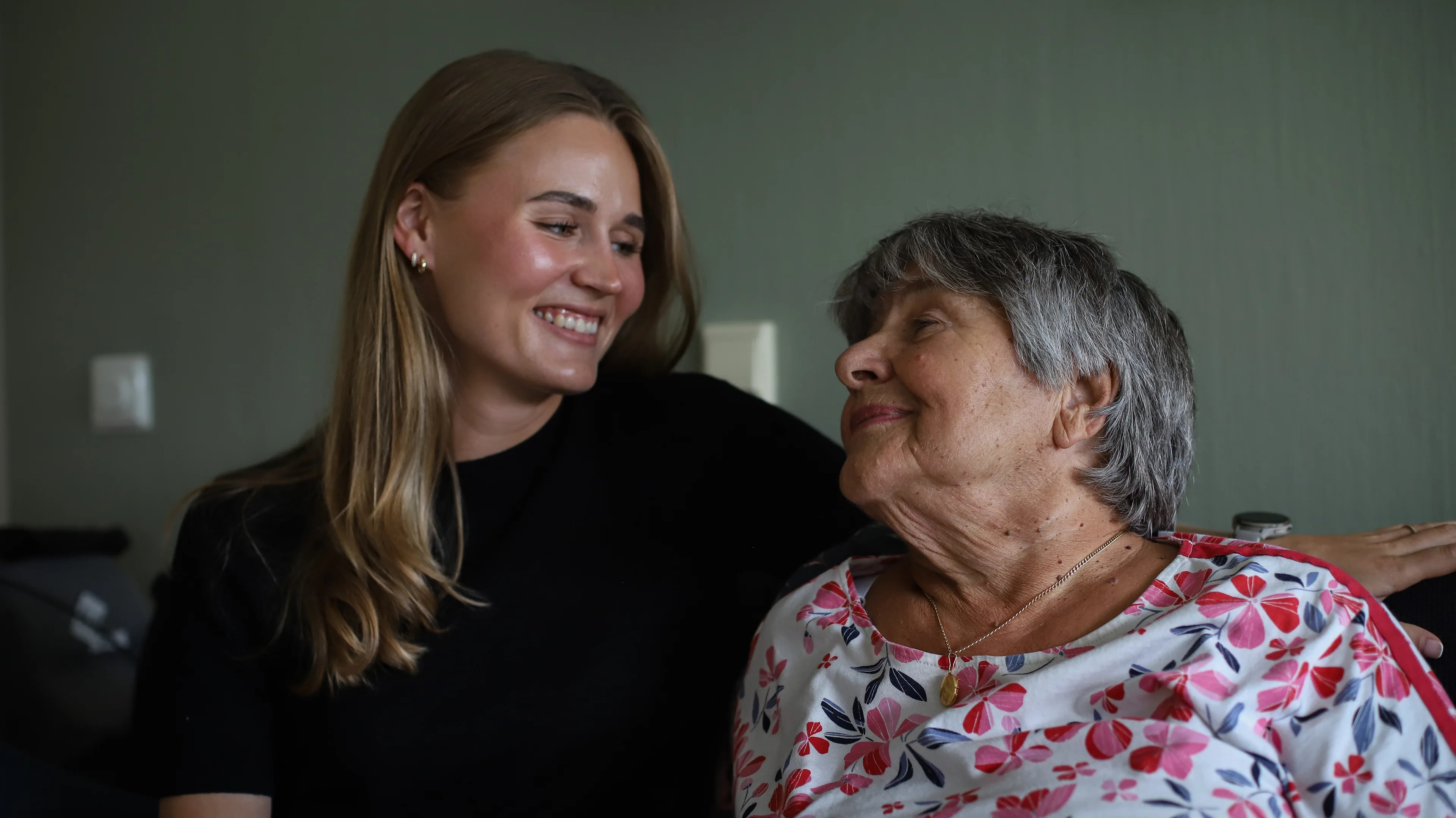 en ung kvinne som sitter ved siden av en eldre kvinne, begge ler og smiler