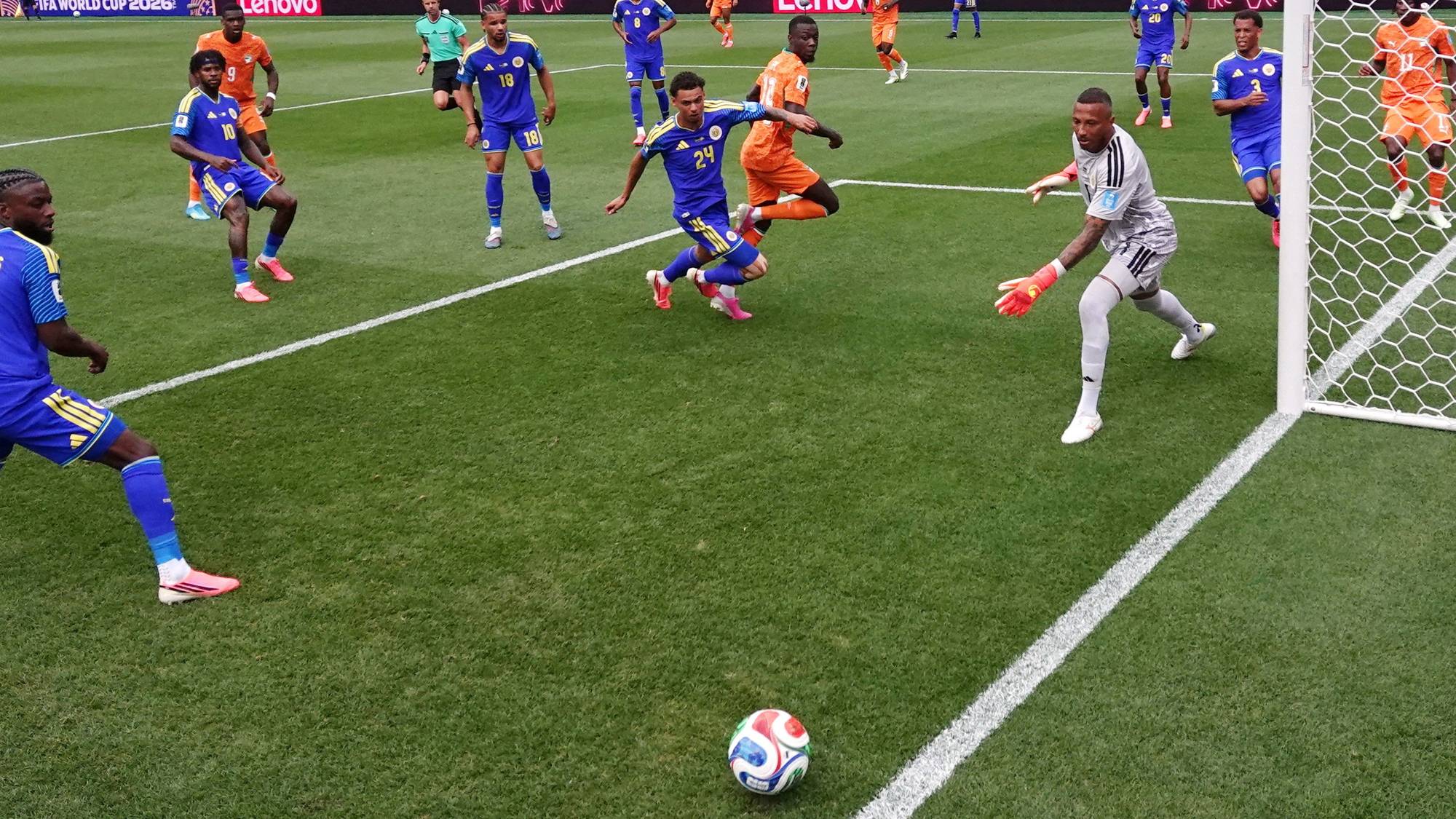 Fotballspillere i blått og oransje drakter spiller kamp på en gressbane. (Bildebeskrivelsen er laget av en KI-tjeneste)