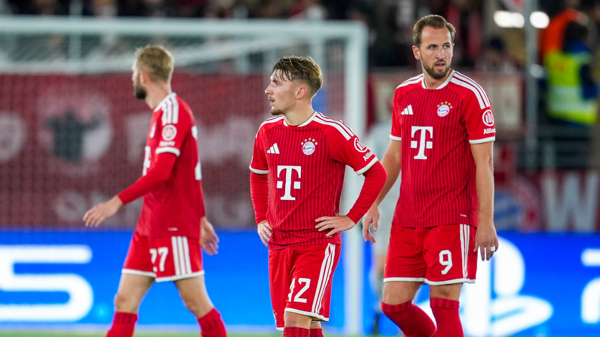 Bayern München-spillere, inkludert Harry Kane, går over banen på en fotballstadion. (Bildebeskrivelsen er laget av en KI-tjeneste)