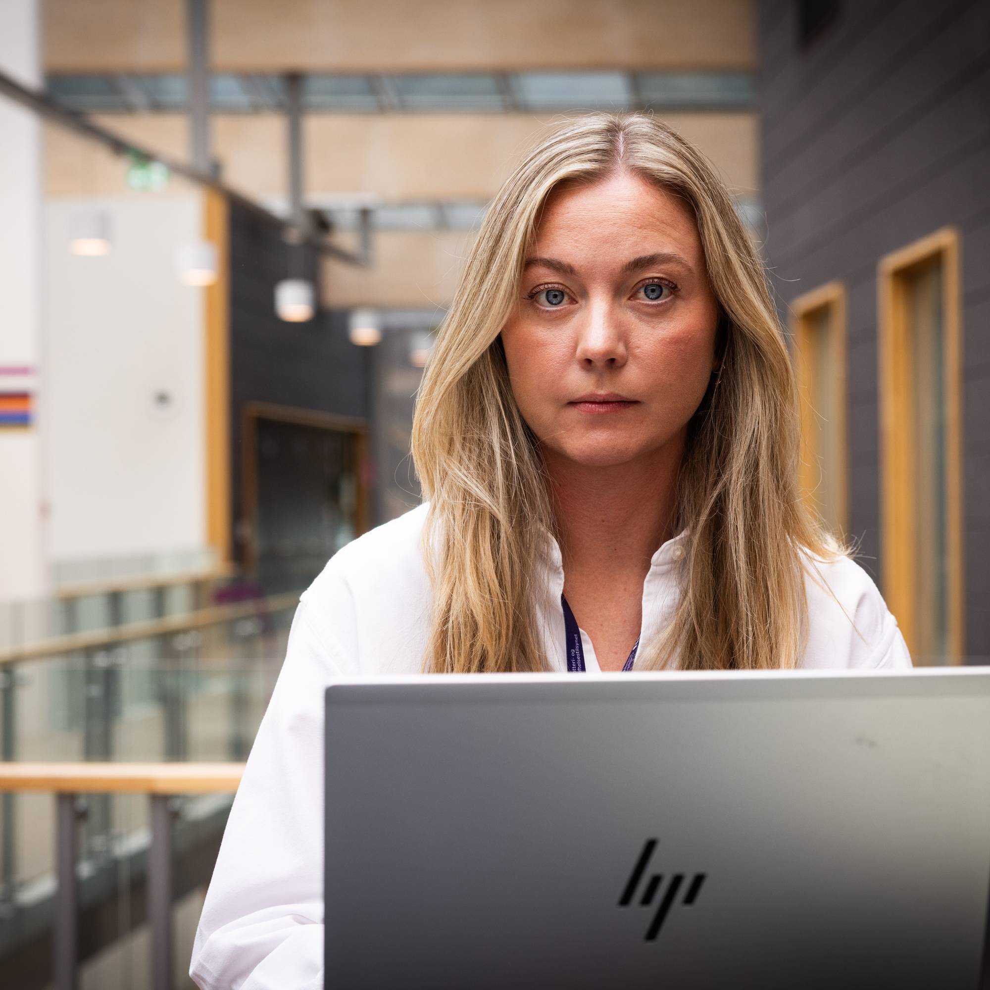 Kvinne i hvit skjorte med bærbar pc foran seg