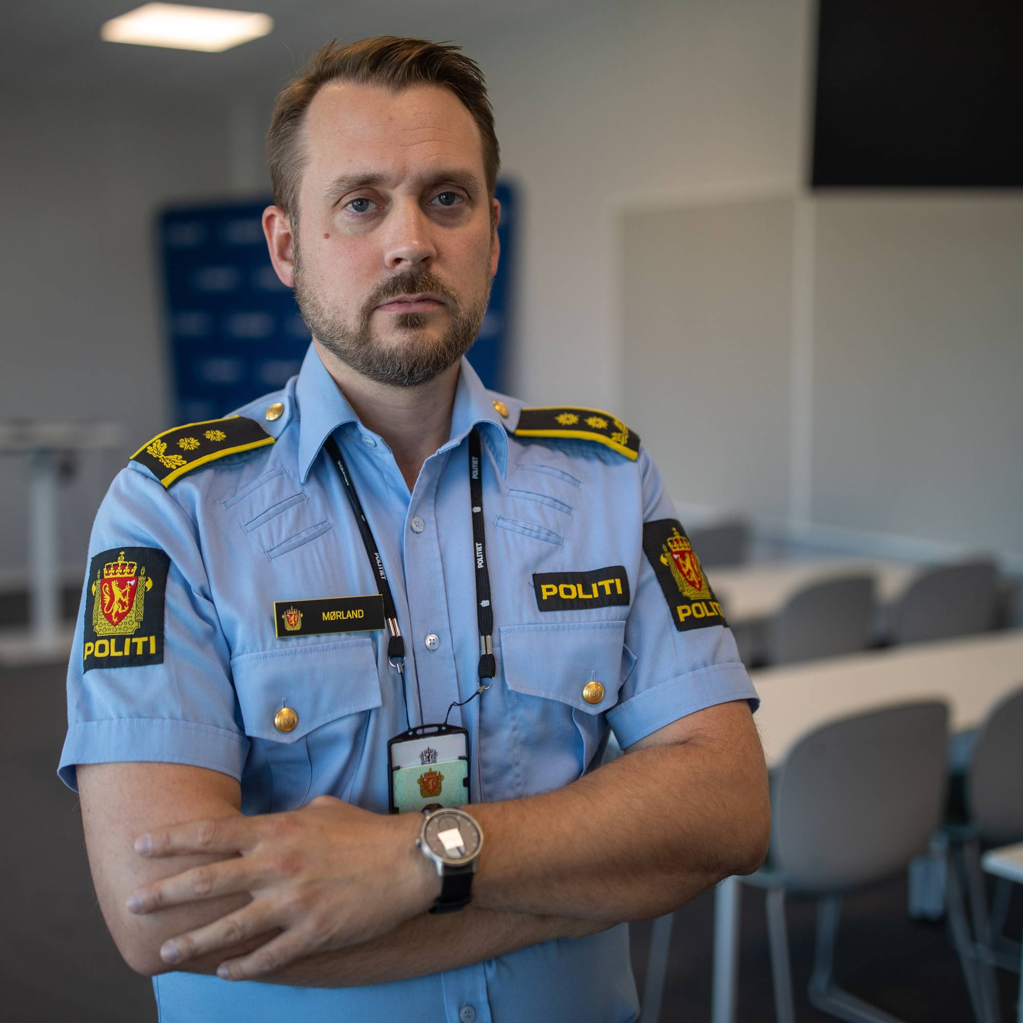 Politimann i uniform med korslagte armer i et møterom. (Bildebeskrivelsen er laget av en KI-tjeneste)