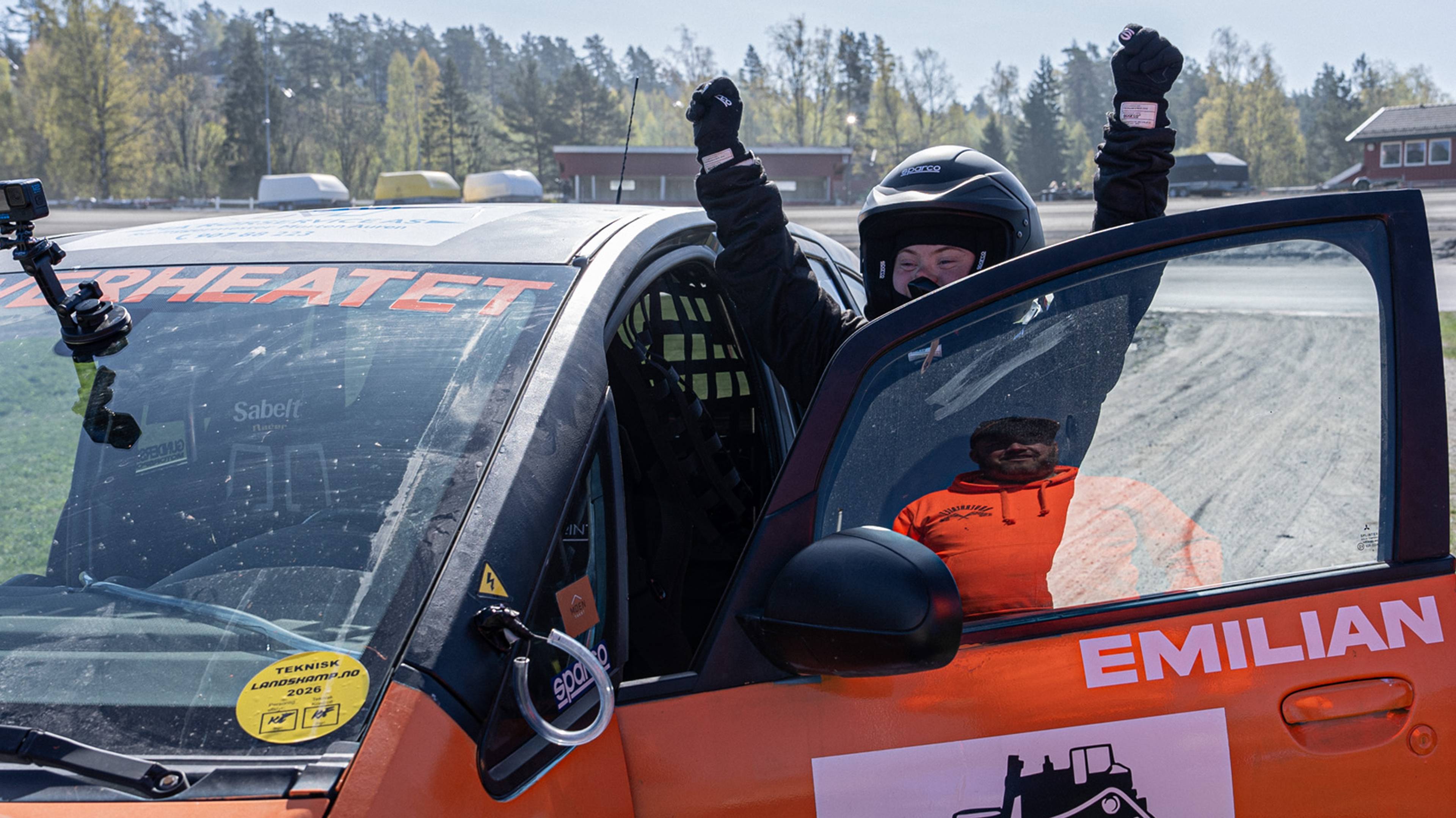 Emilian bråten står med hjelm etter å ha gått ut av bilen og holder armene fornøyd opp i været