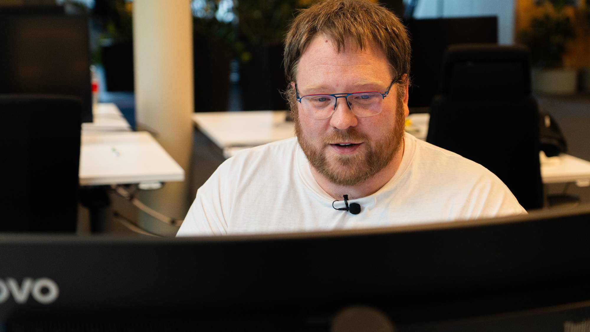 viser en mann med briller og skjegg som ser på en dataskjerm