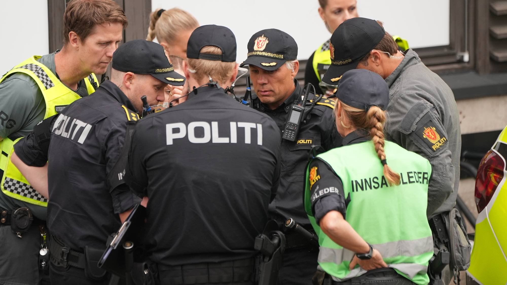 Politibetjenter i uniform samlet i en gruppe utendørs for å samtale. (Bildebeskrivelsen er laget av en KI-tjeneste)