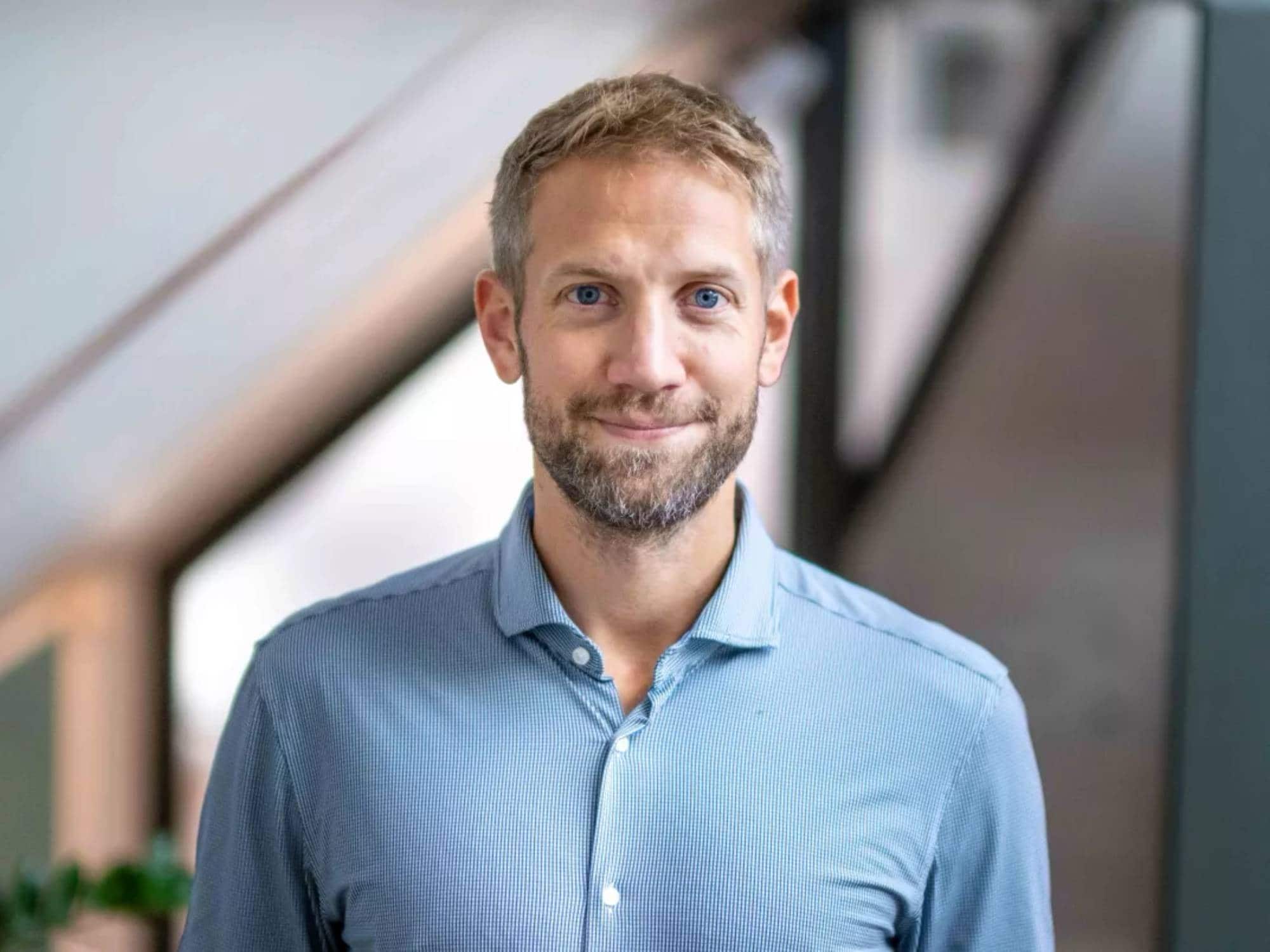 En blond mann med skjegg i blå skjorte